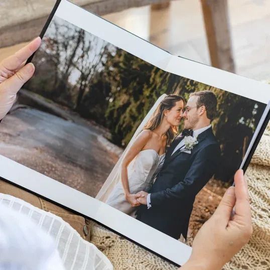 Hands holding wedding photo album showing romantic couple portrait.