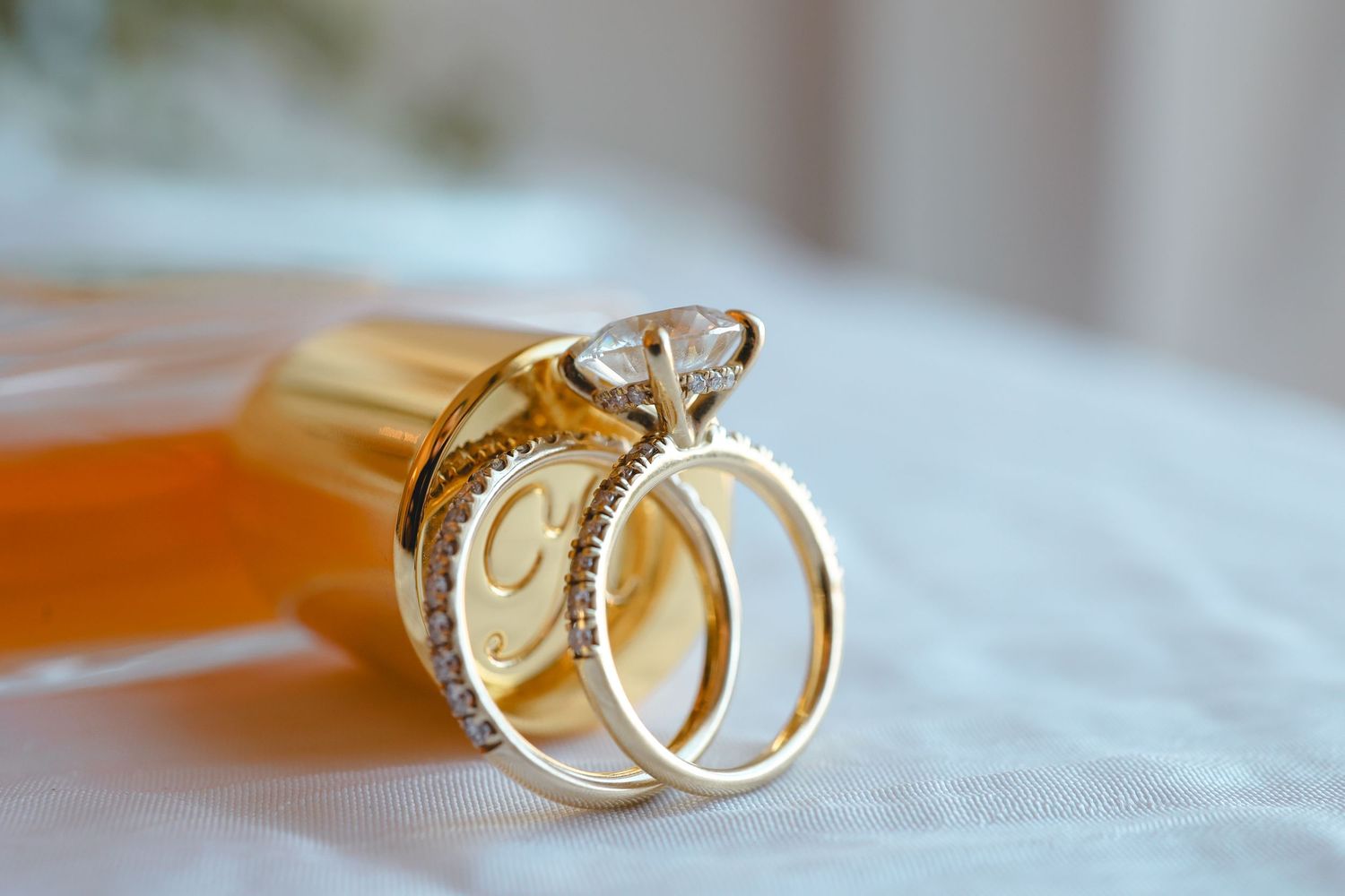 Close-up view of two gold wedding rings on white fabric showing intricate details and design.
