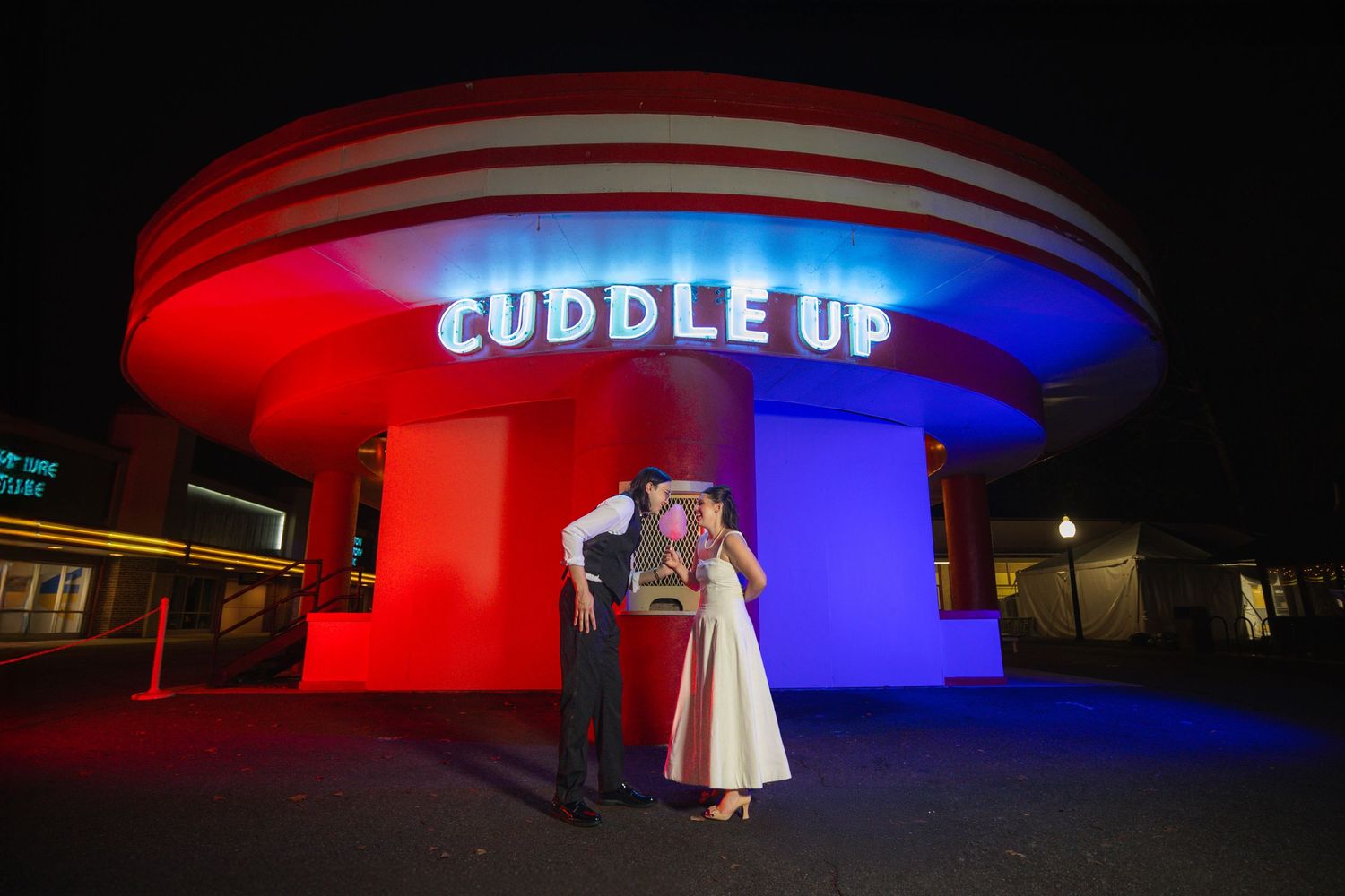 Illuminated building exterior glows with dramatic red and blue lighting against dark night sky.