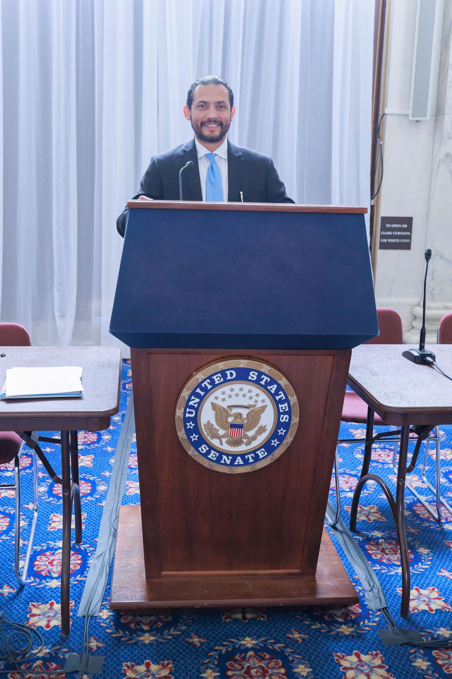 Three wooden podiums with the Vice Presidential seal stand in a row against a blue patterned backdrop.