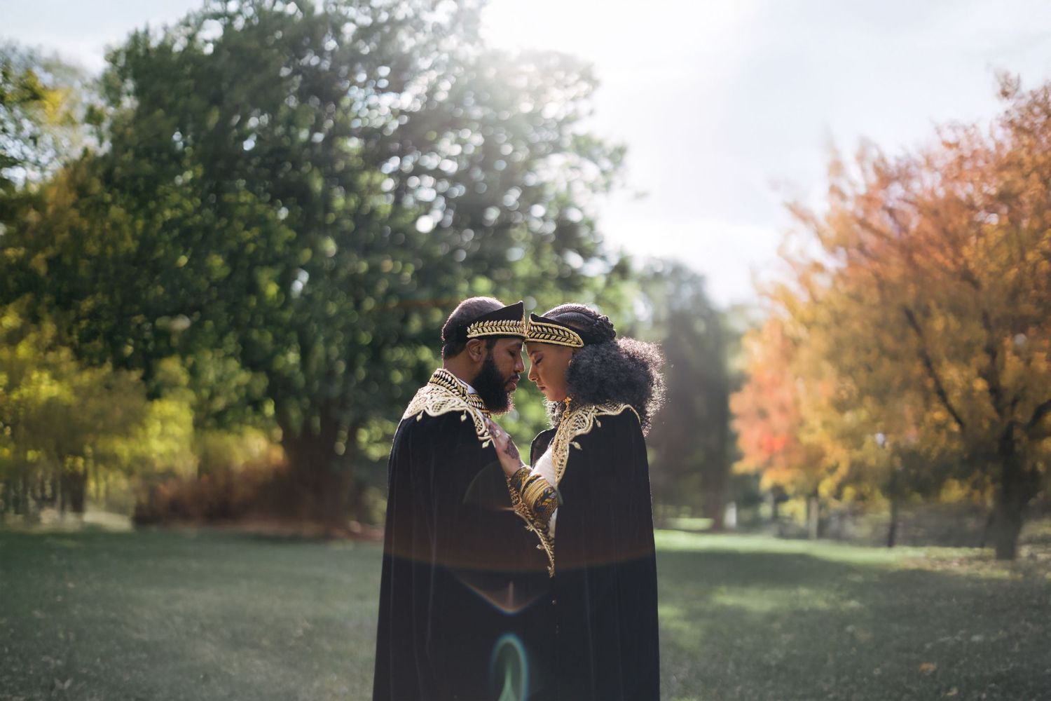Silhouetted couple sharing intimate moment in autumn park setting.