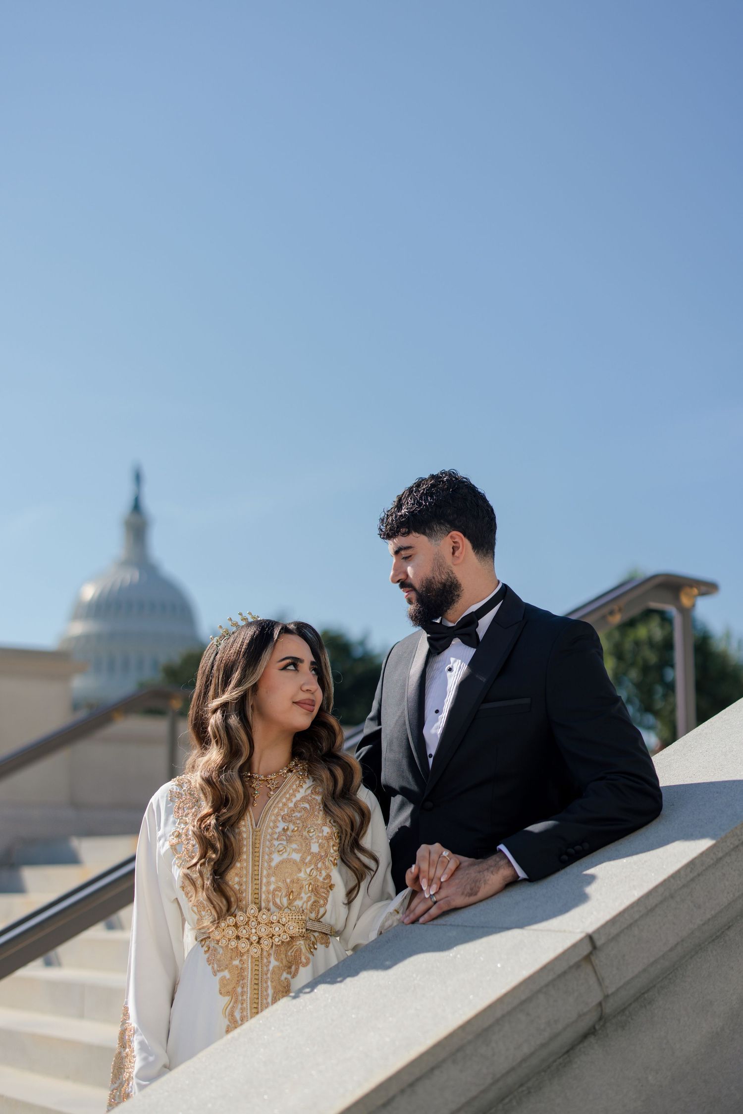 A couple in traditional wedding attire shares romantic moments near the US Capitol building in Washington DC.
