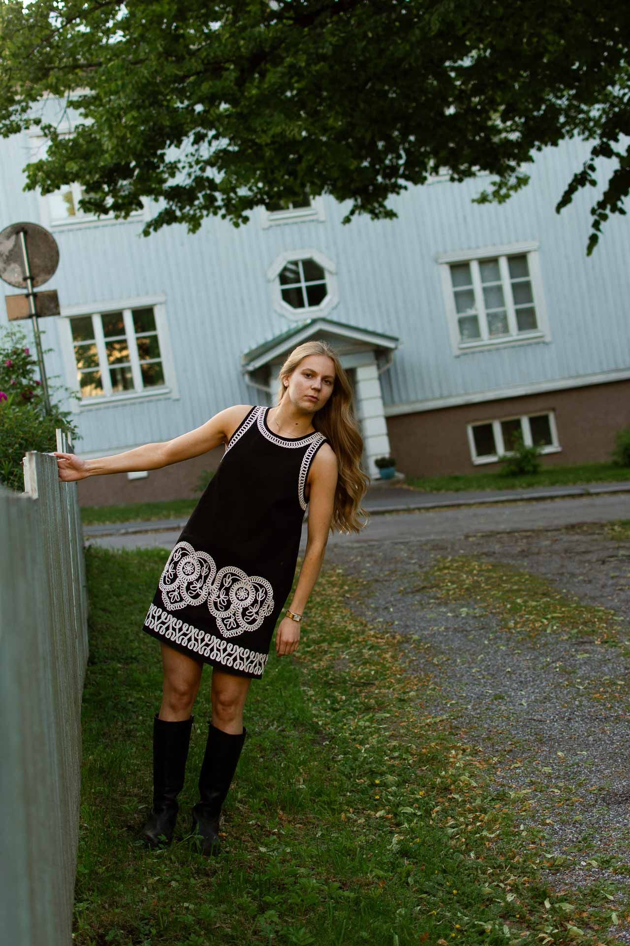 Nuori nainen nojaa kaiteeseen yllään mekko.