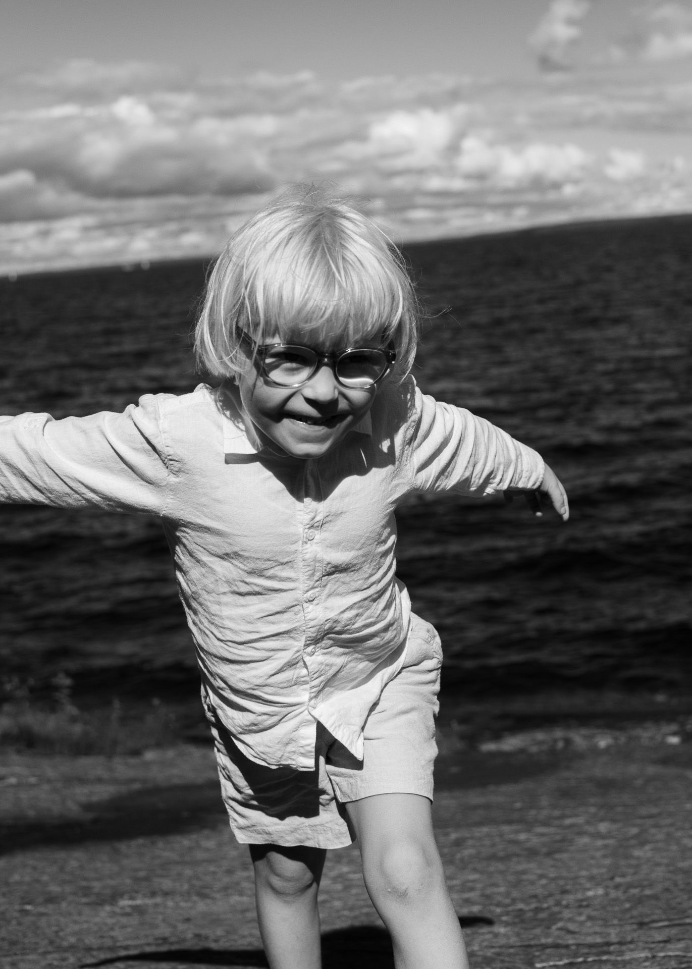 Poika juoksee kameraa kohti nauraen kädet levällään.