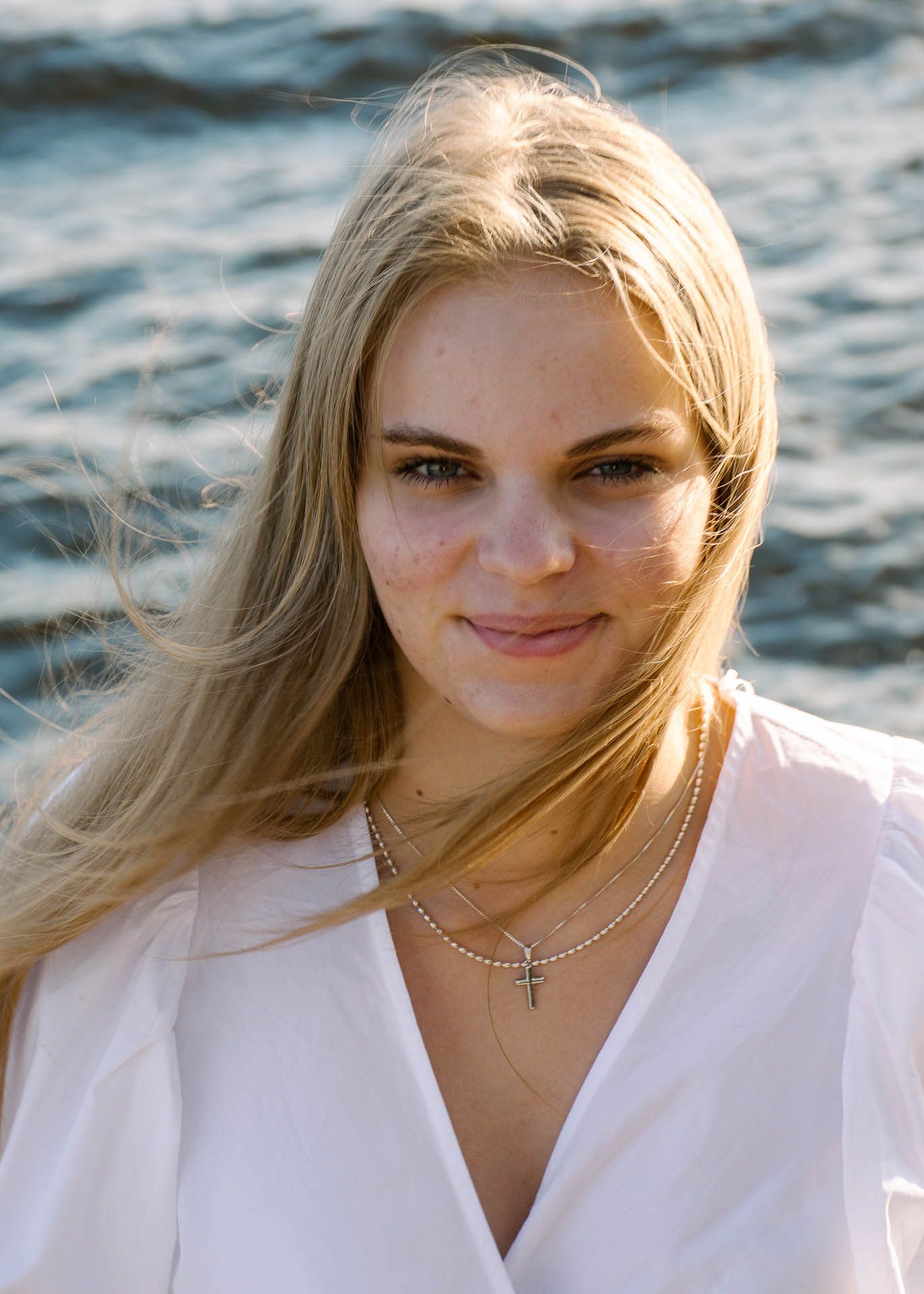 Nuori tyttö lähikuvassa, ja takana näkyy järvi.
