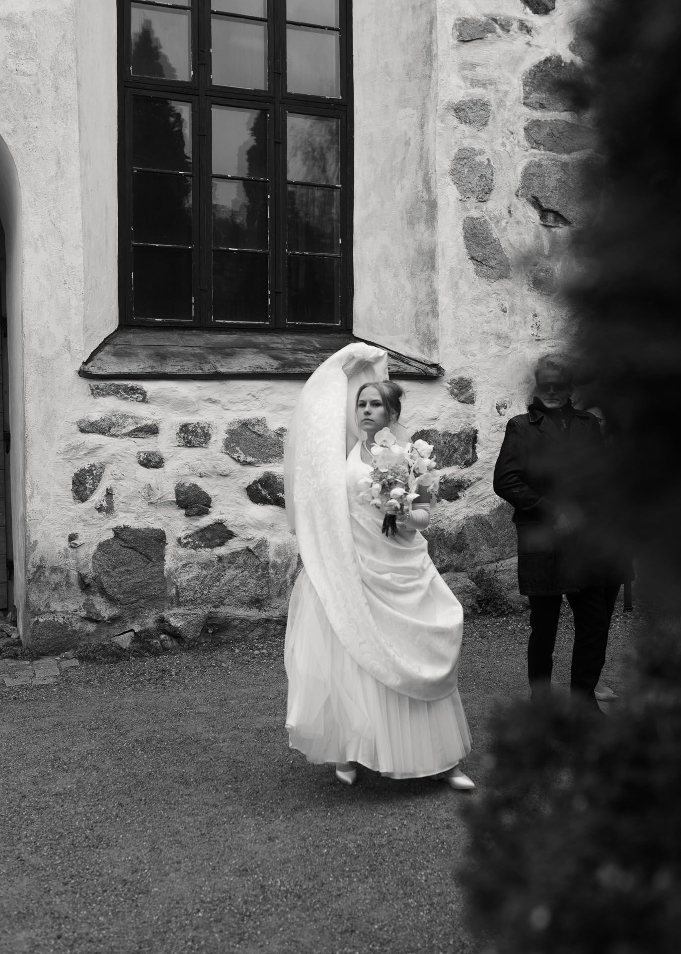 Morsian seisoo kirkon edustalla, ja nostaa mekkonsa helmaa korkealle.