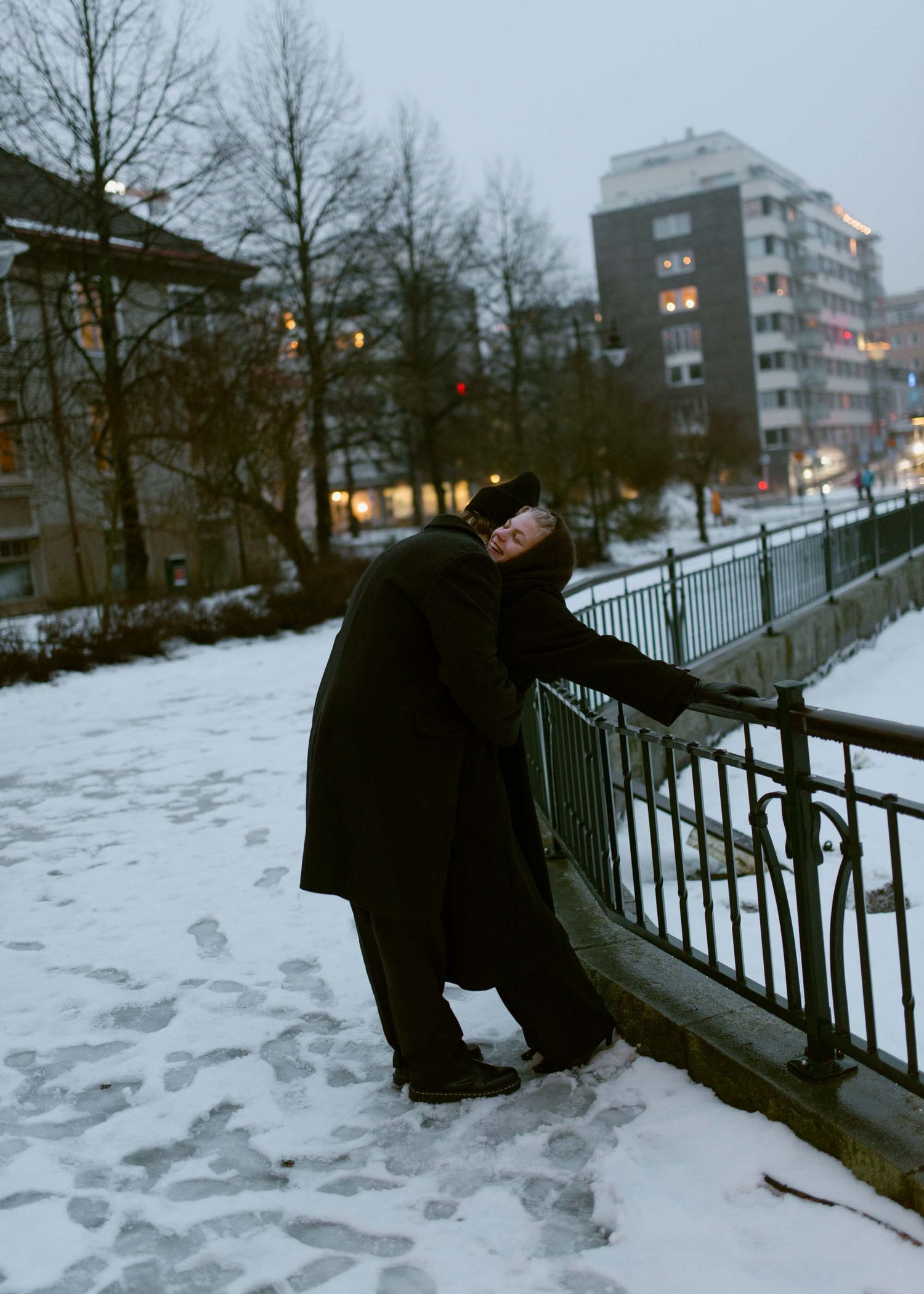 Pariskunta toisiaan vasten nojaten hämärtyvässä illassa.