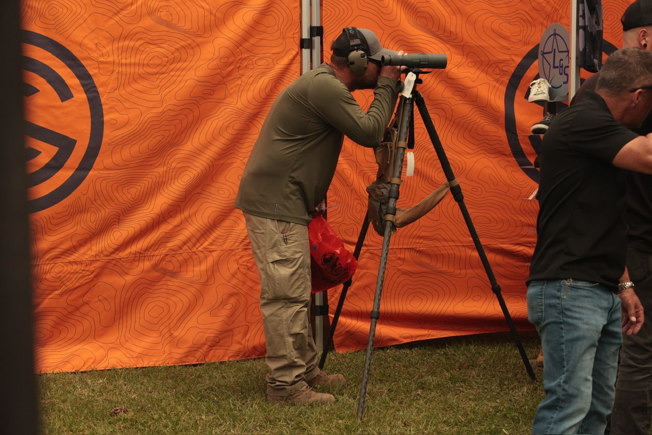 Orange backdrop setup at an outdoor event with camera equipment and lighting gear.