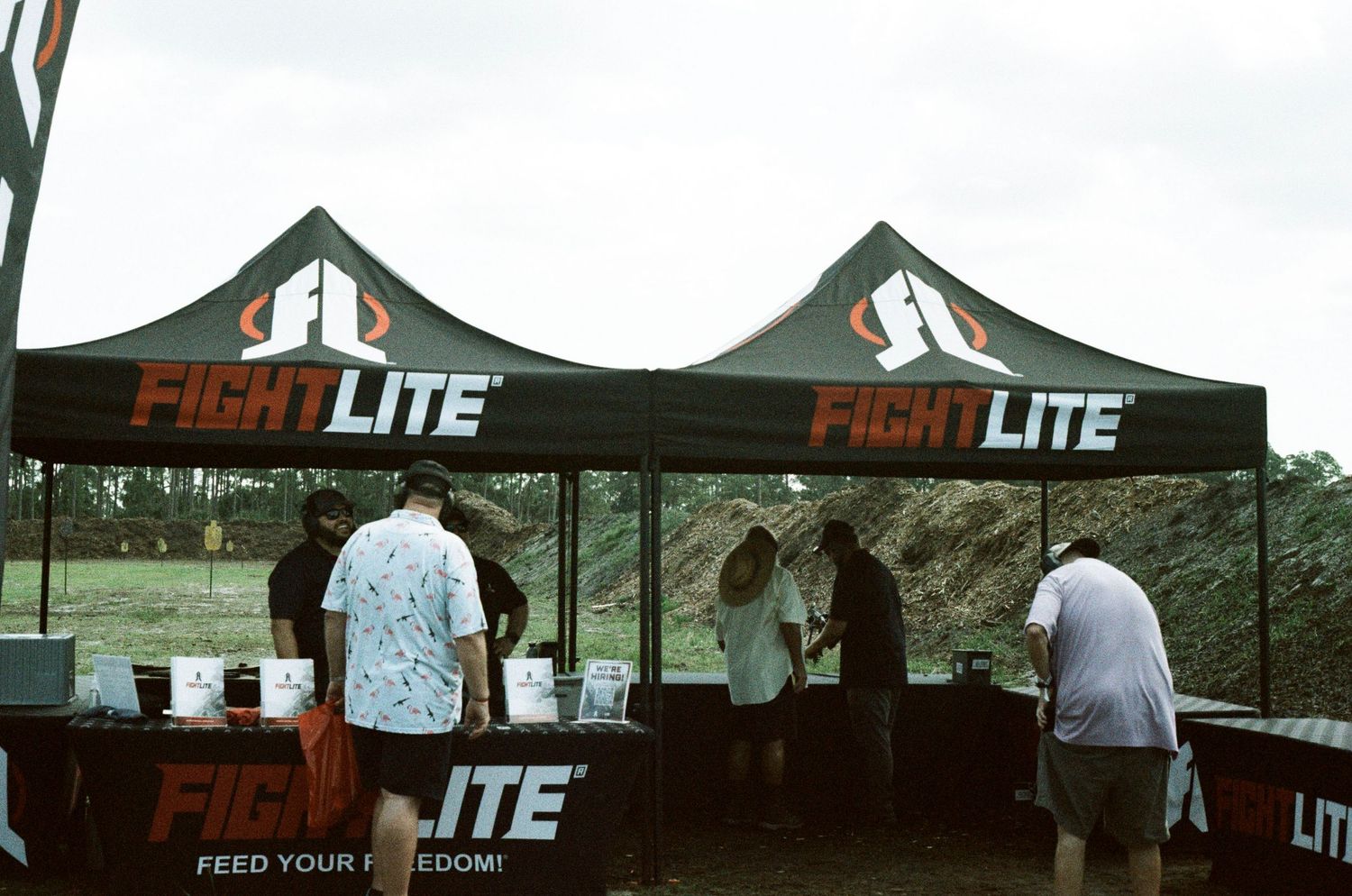 FightLite branded black canopy tents with people browsing products at outdoor expo.