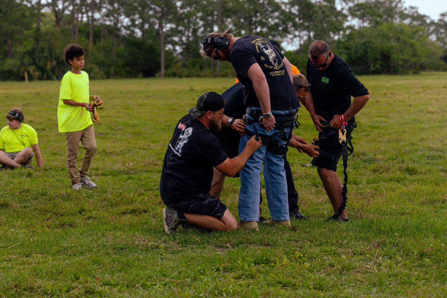 Group of people kneeling in grass field during outdoor training or event.