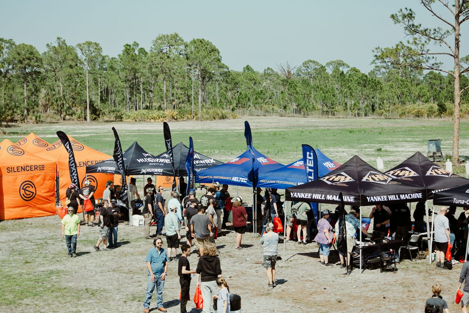 Aerial view of vendor tents and crowds at an outdoor firearms and shooting sports expo.