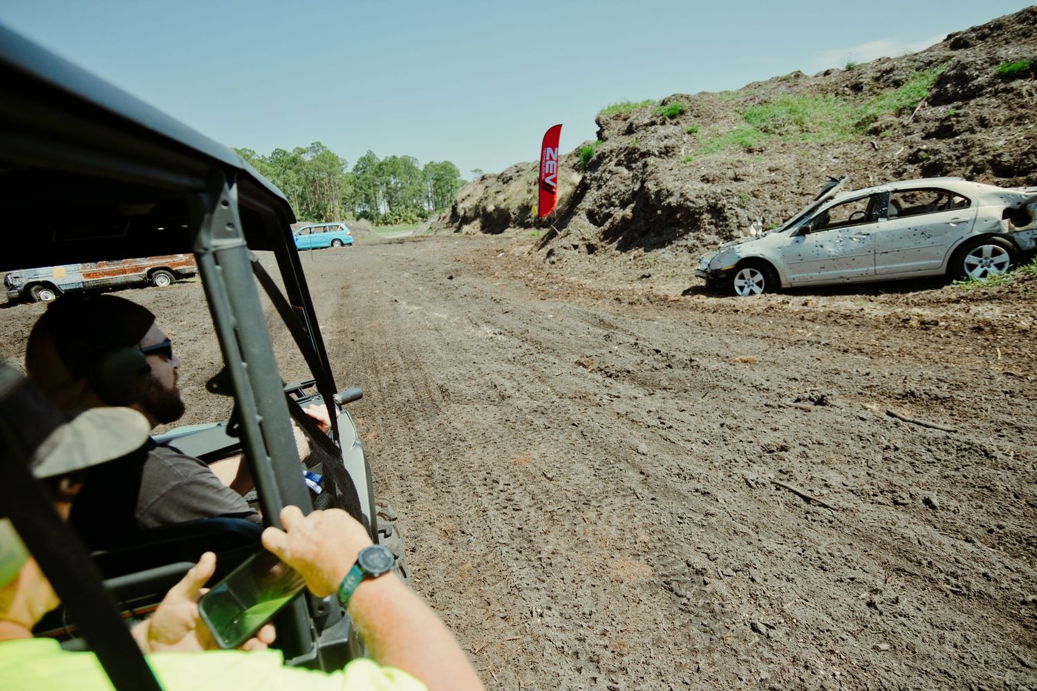 View from off-road vehicle driving on muddy dirt track at outdoor adventure event.
