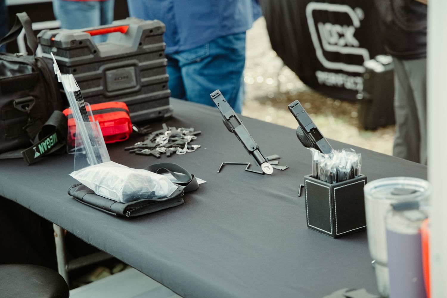 Glock firearms accessories and tools displayed on a table at an outdoor gun show event.