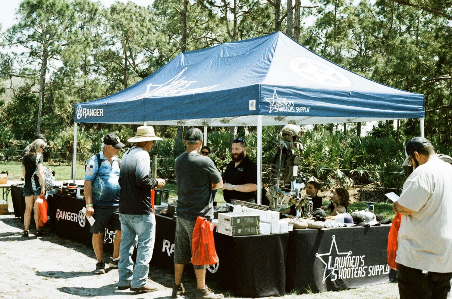 Blue Ranger canopy tent with vendors displaying tactical and outdoor gear at an outdoor expo event.