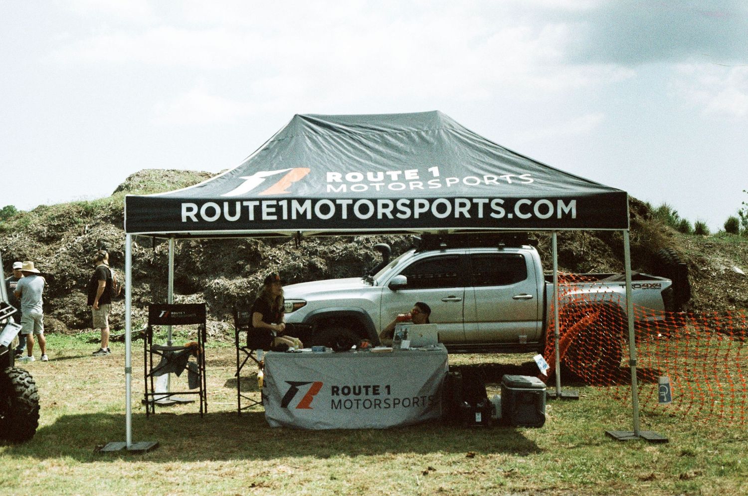 Route 1 Motorsports branded tent display with off-road vehicle at outdoor motorsports expo event.