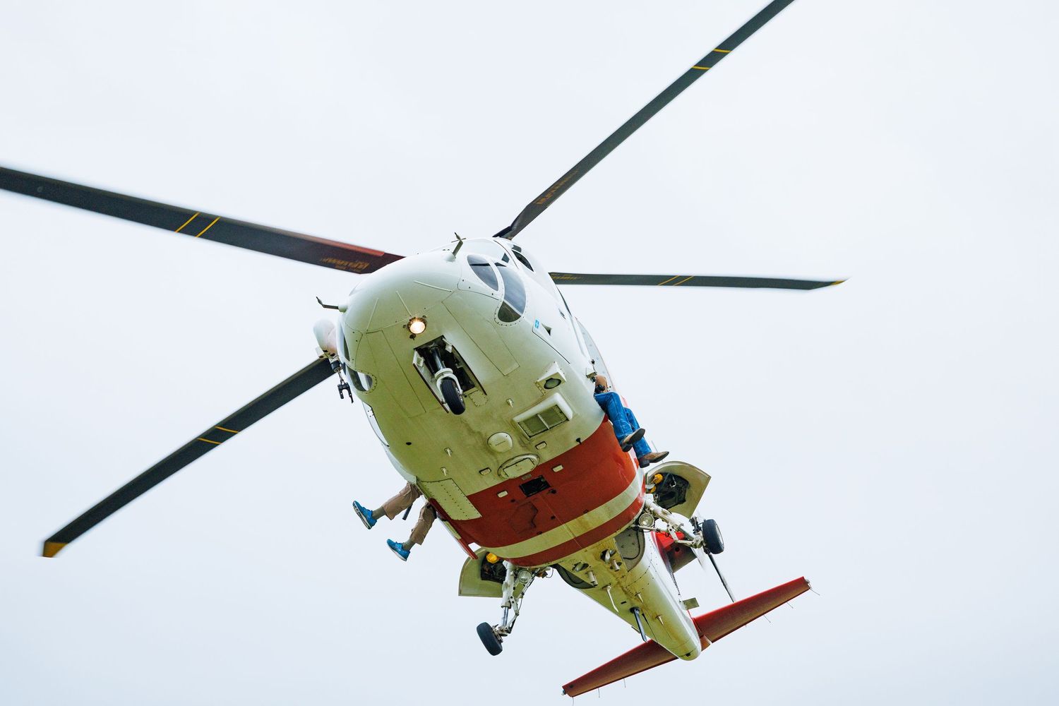 White helicopter in flight against bright overcast sky.