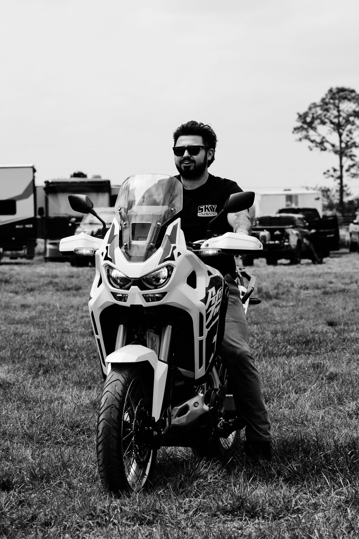 Three white sport motorcycles lined up on grass field in black and white photography.