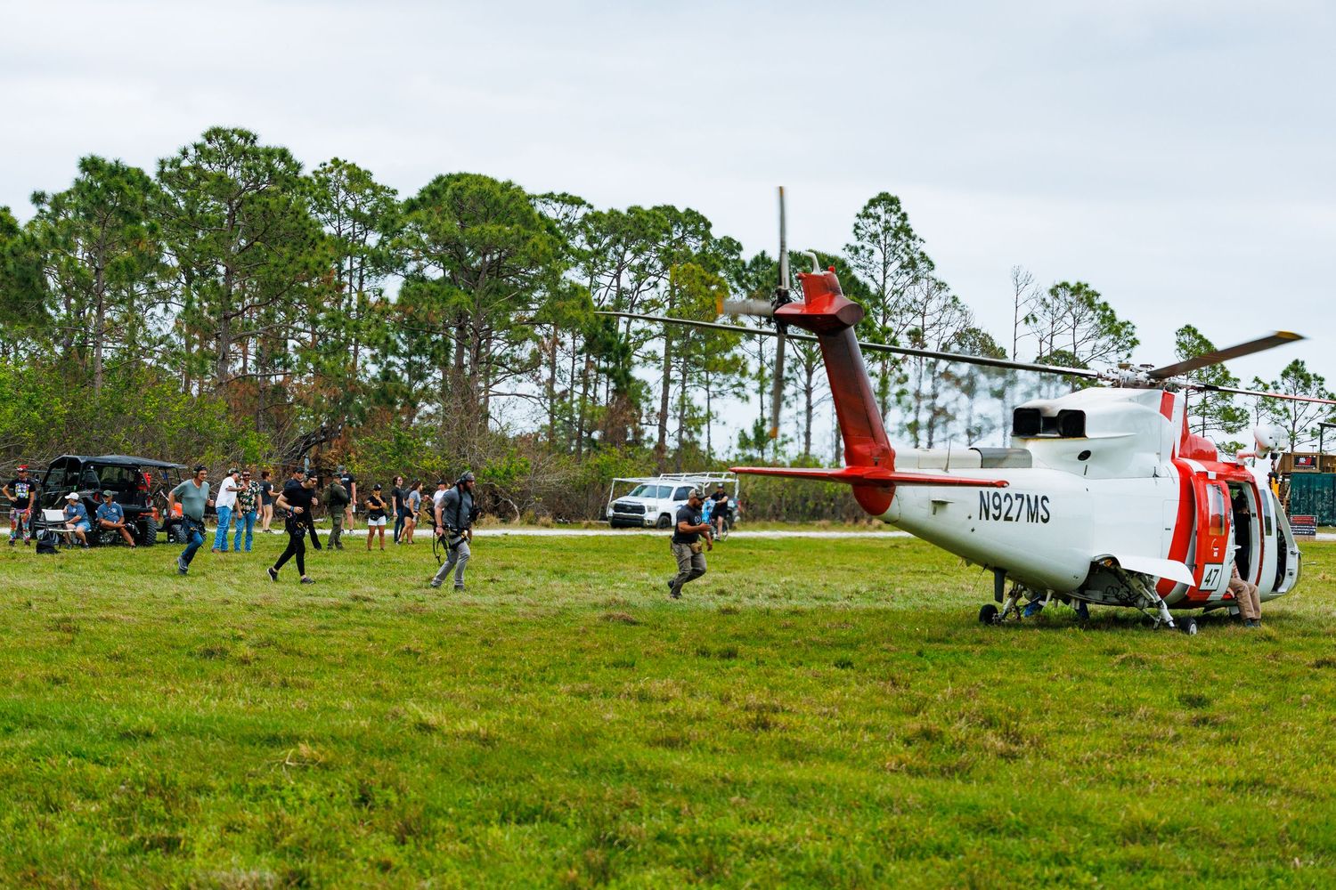 Coast Guard helicopter displayed on grassy field with spectators nearby.