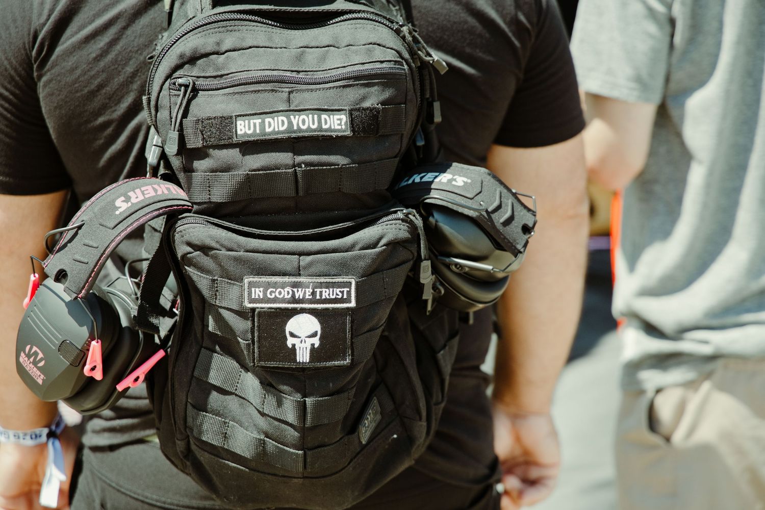 Black tactical backpack with Punisher skull patch and motivational morale patches at gun event.