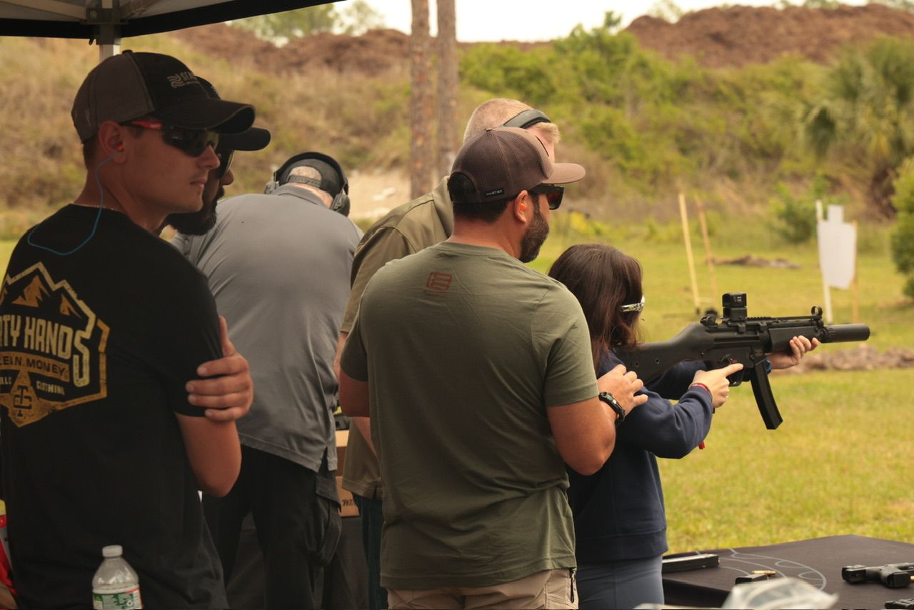 People practicing shooting at an outdoor range with targets in the distance.