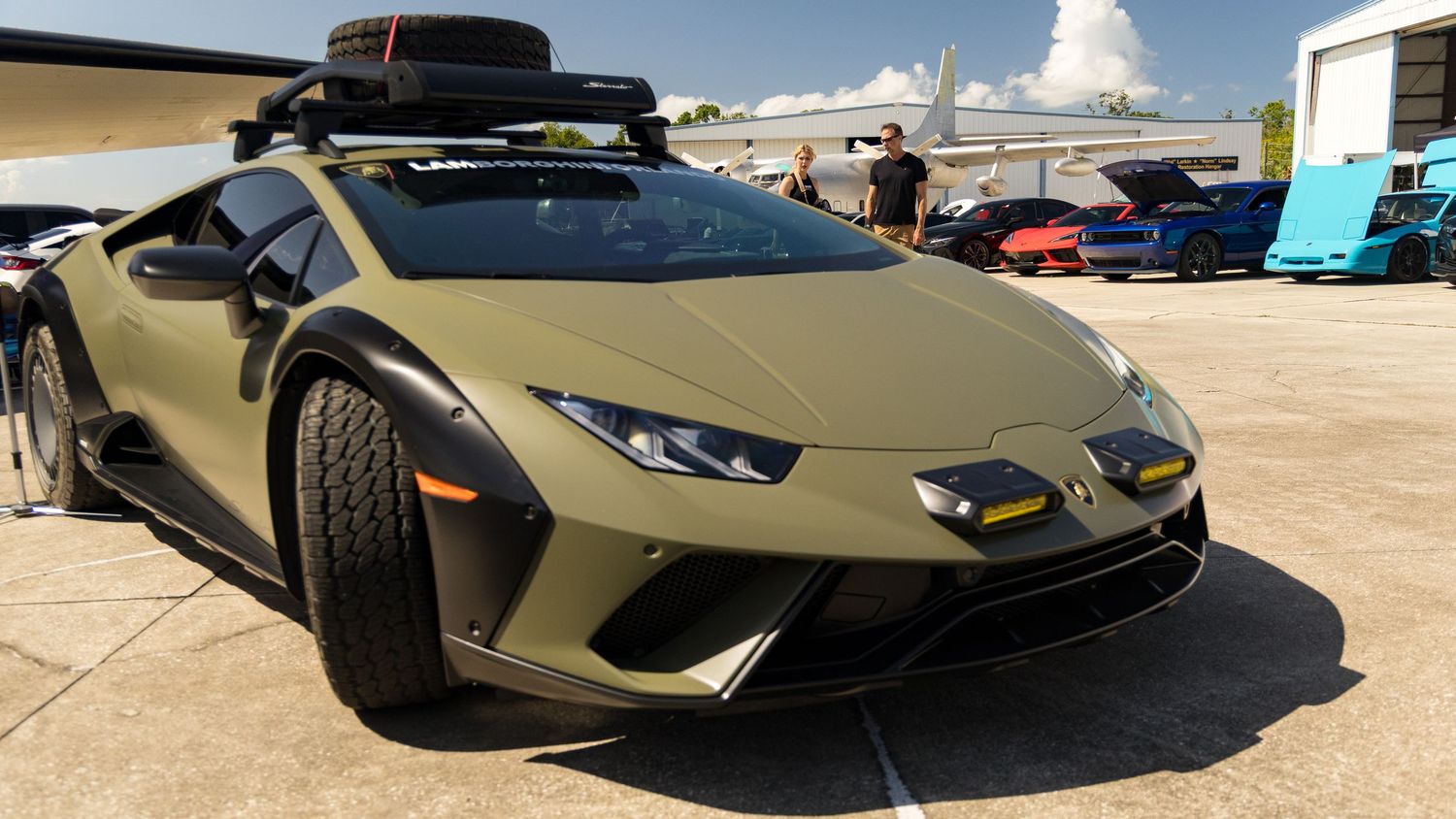 Modern supercars including a Lamborghini Aventador displayed in a panoramic view at an outdoor showroom.