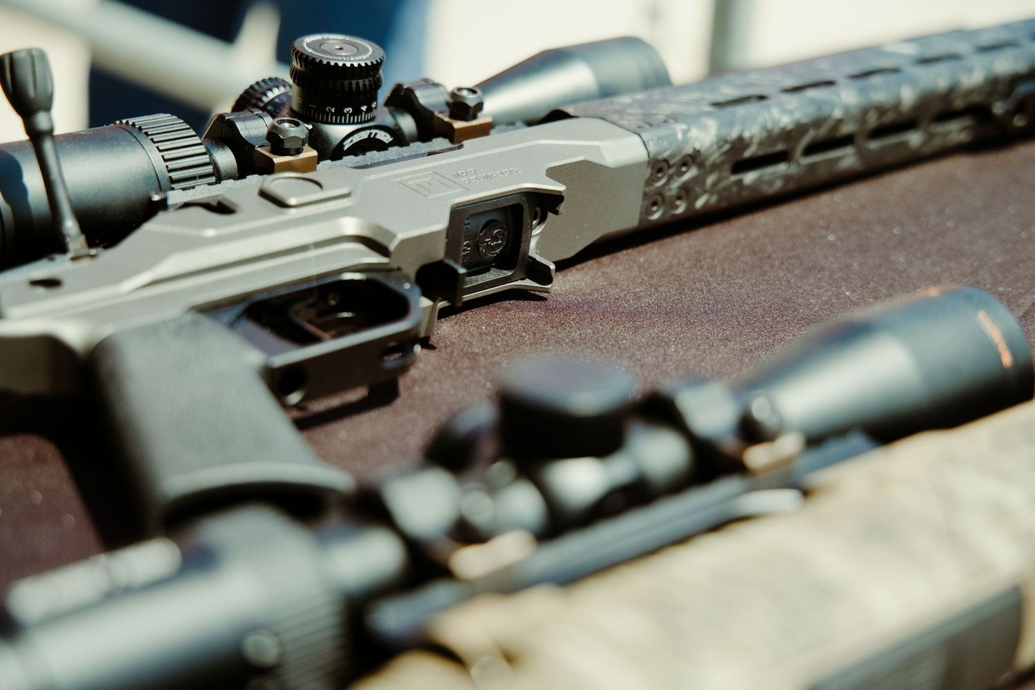 Close-up of precision bolt-action rifle with tactical scope on display at a gun show.