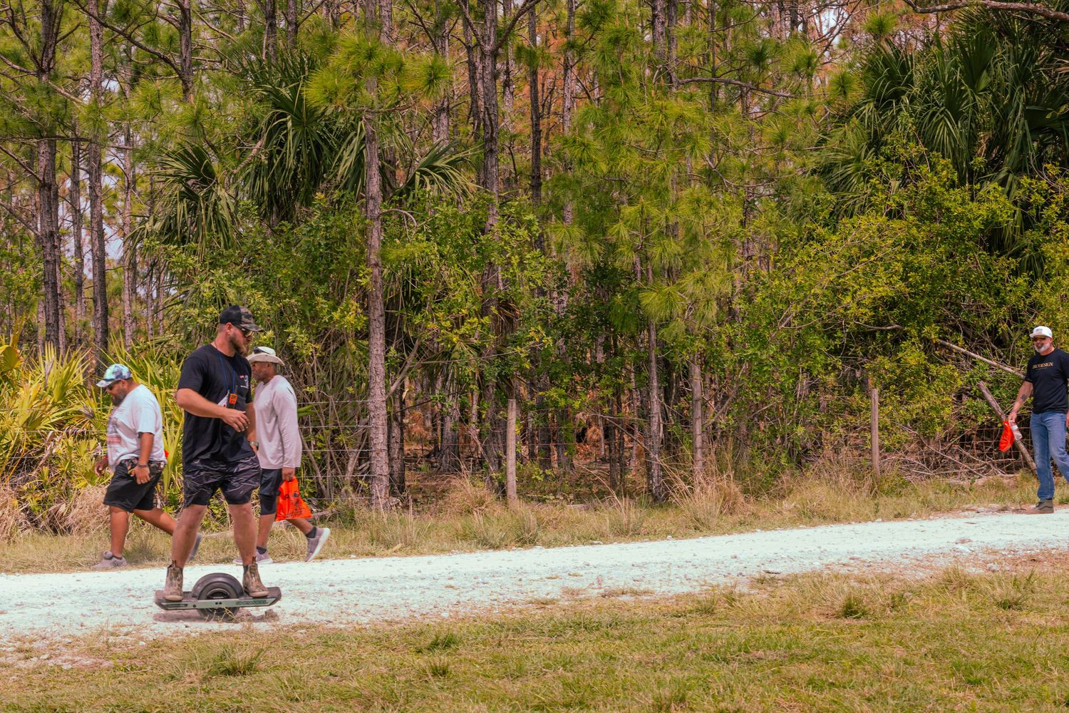 People walking along a sandy trail through a wooded area during an outdoor event.
