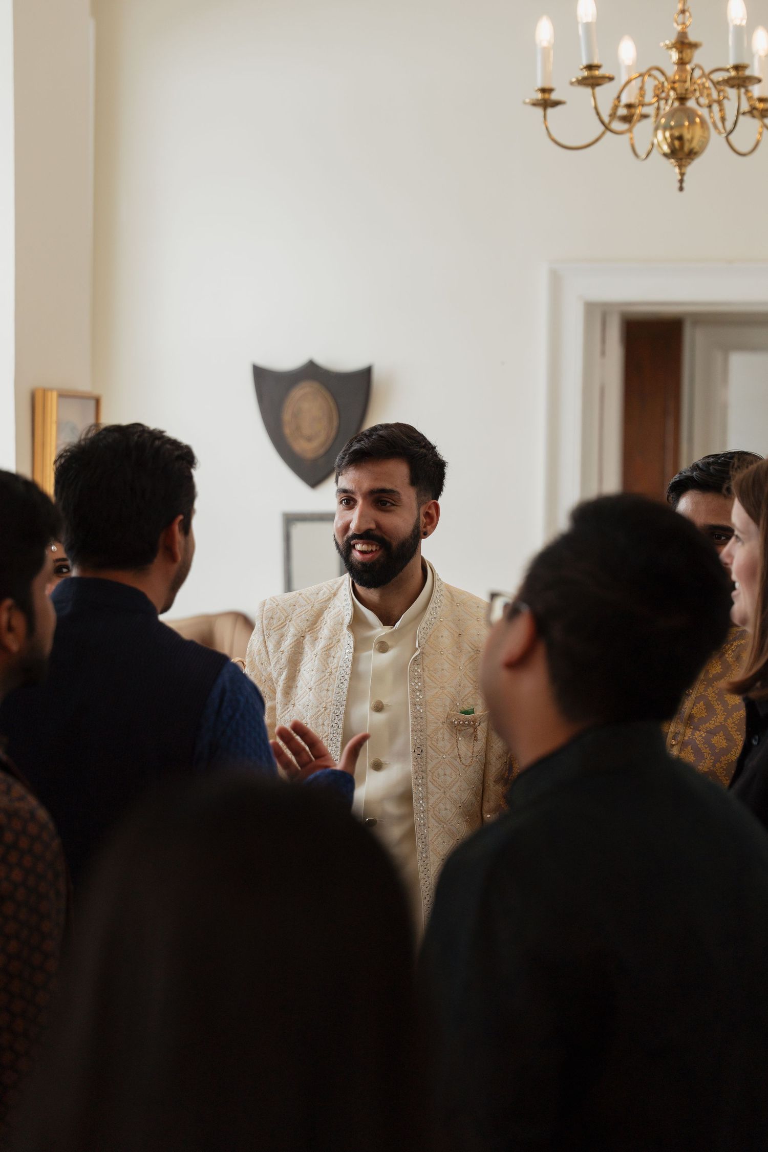 People gathered in an elegant room with a chandelier and someone wearing traditional formal attire.