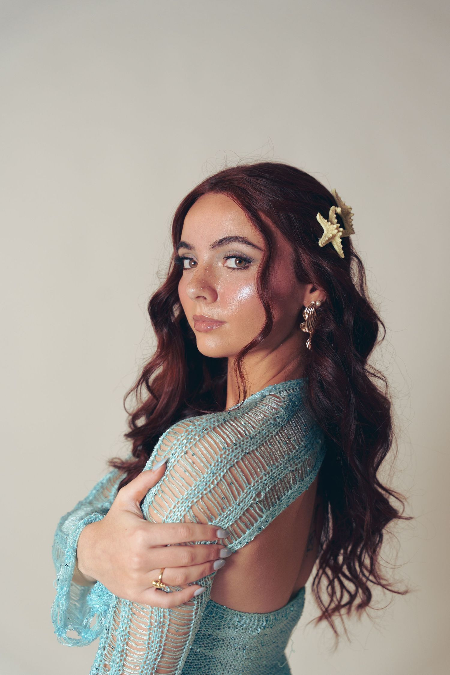 A romantic portrait in a turquoise lace dress with long wavy dark hair adorned with a floral hair accessory.