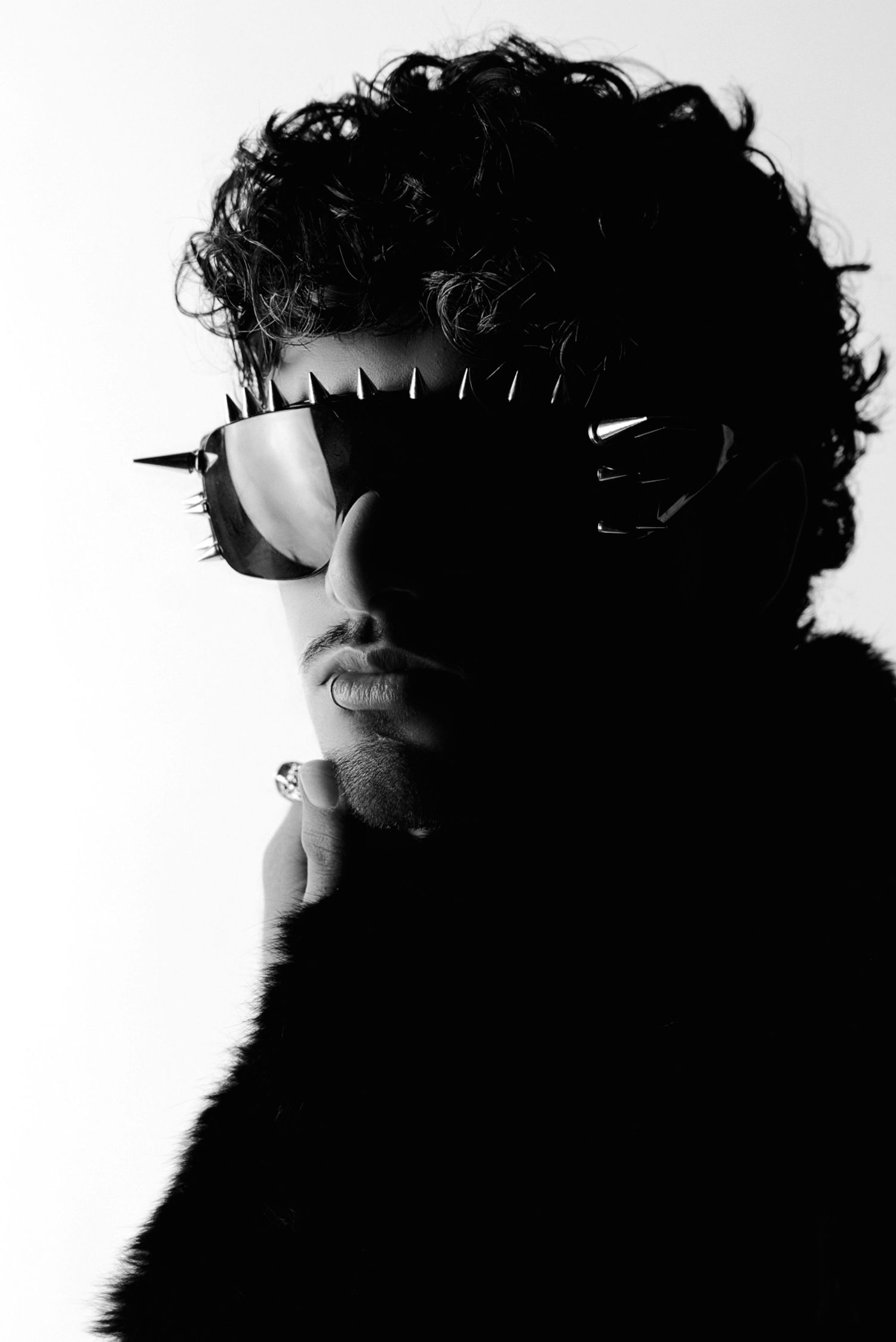 Dramatic silhouette portraits in profile view showing a curly-haired figure against white background with sunglasses.