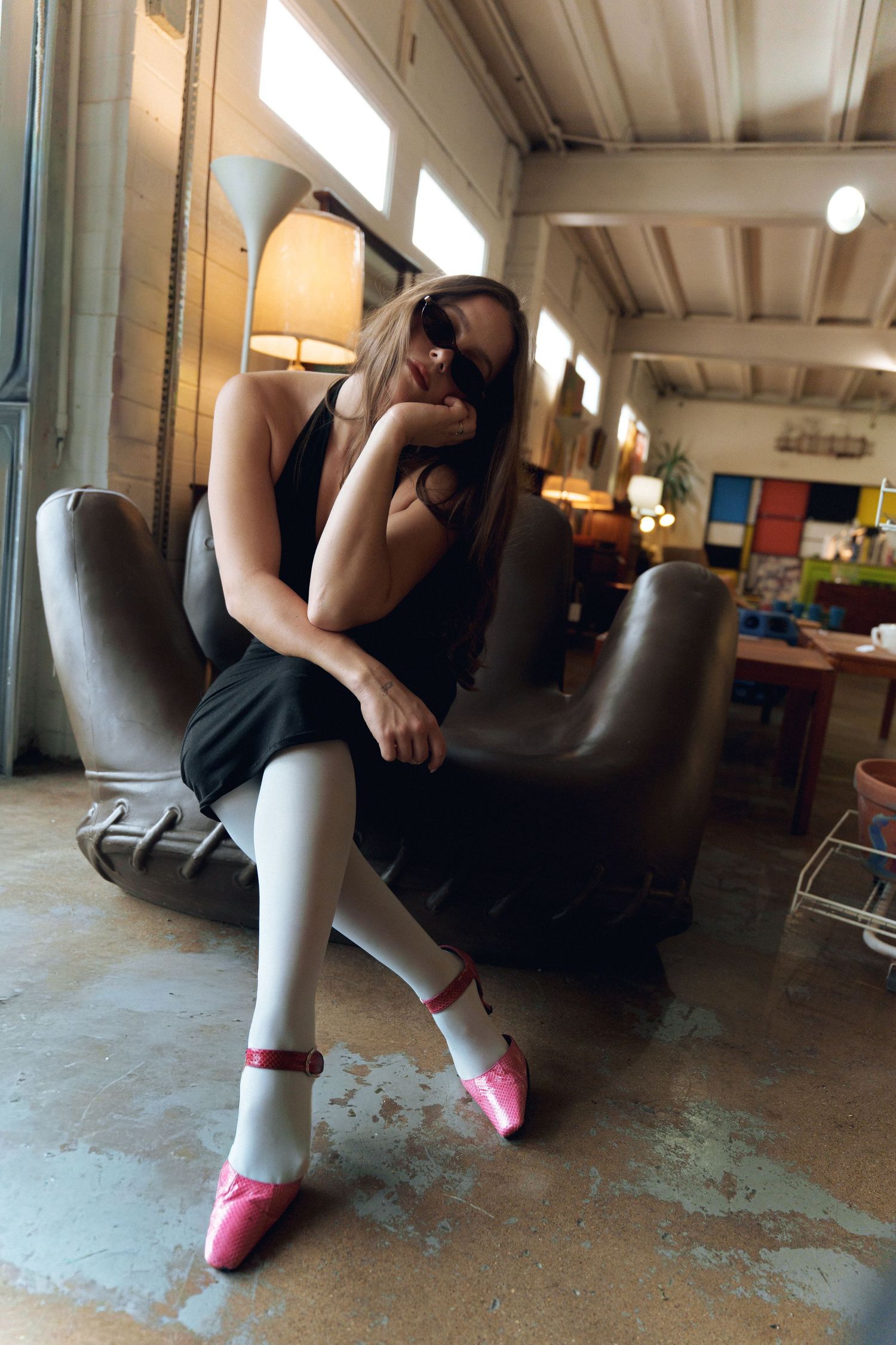 Person in black athletic wear and bright pink socks doing stretching exercises on concrete floor in an indoor space.