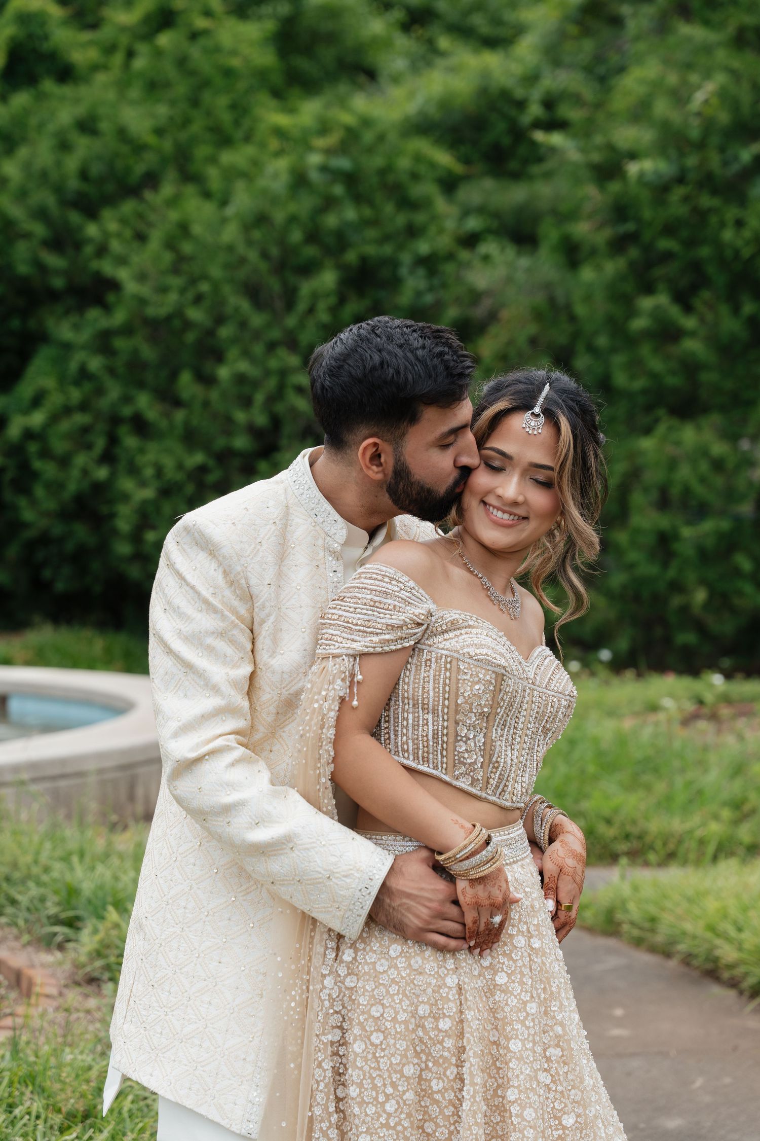 A romantic moment captured between newlyweds wearing coordinated cream-colored traditional wedding attire.