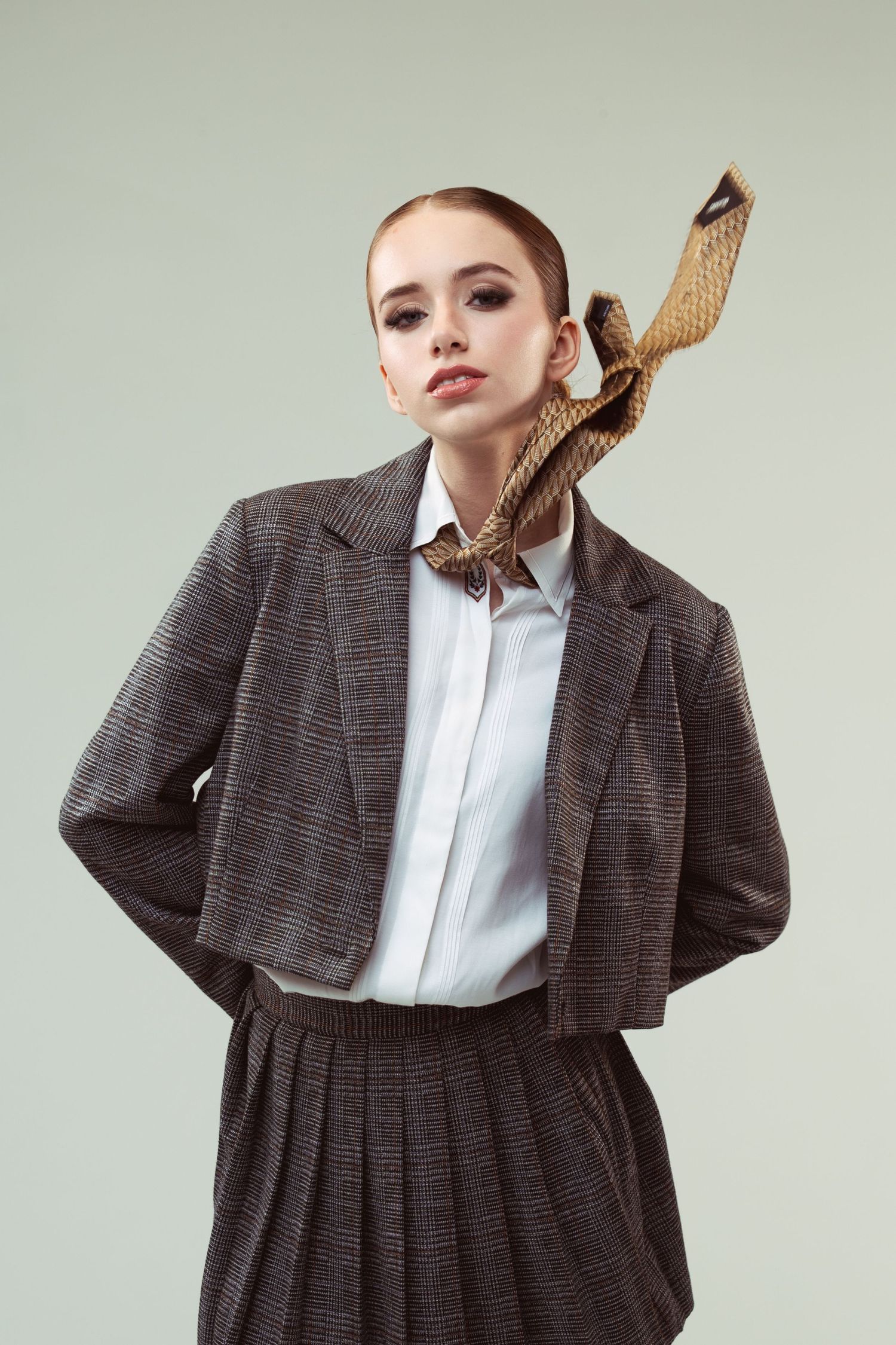 Model in vintage-inspired gray suit and white shirt with snake print scarf styled in retro fashion.