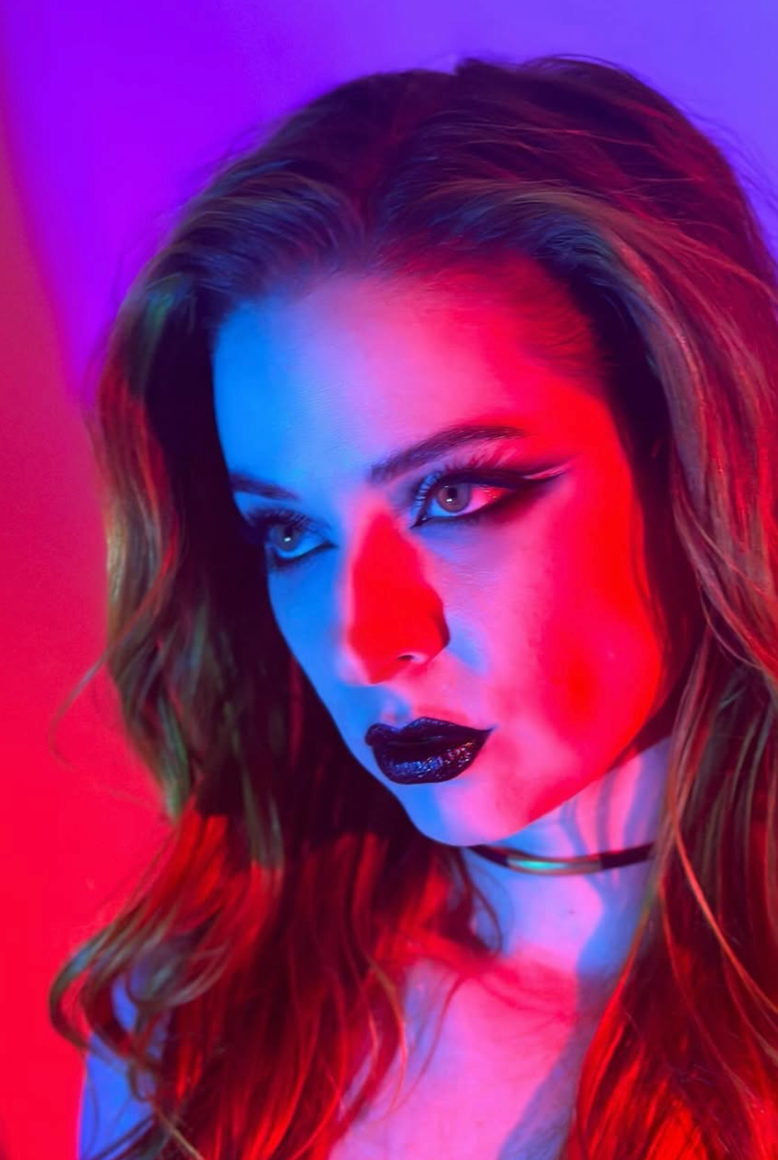 Artistic portrait series with dramatic red and blue lighting creating moody neon-colored effects on model against dark background.