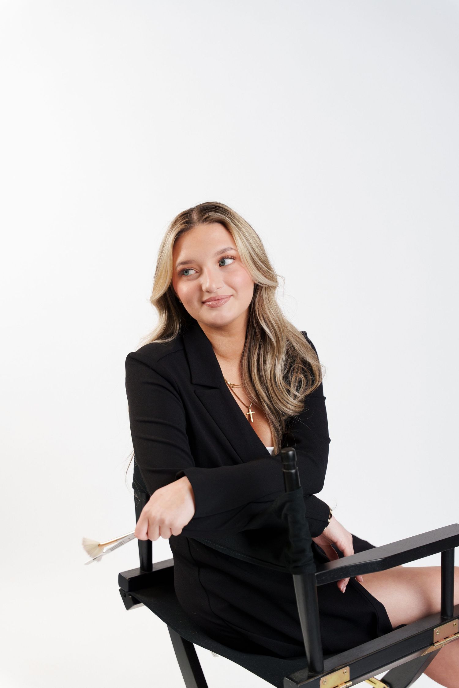 Professional model wearing a black blazer poses against white background in a dynamic editorial style shoot.