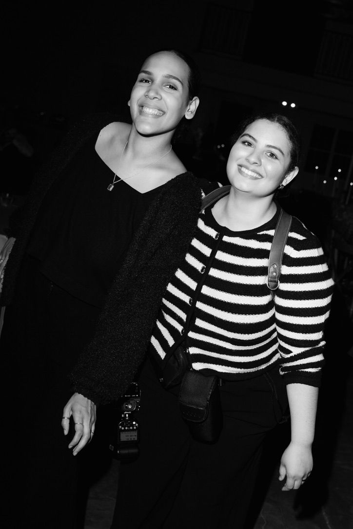 Two smiling women posing together in black and white photo, one in striped sweater, one in black top.