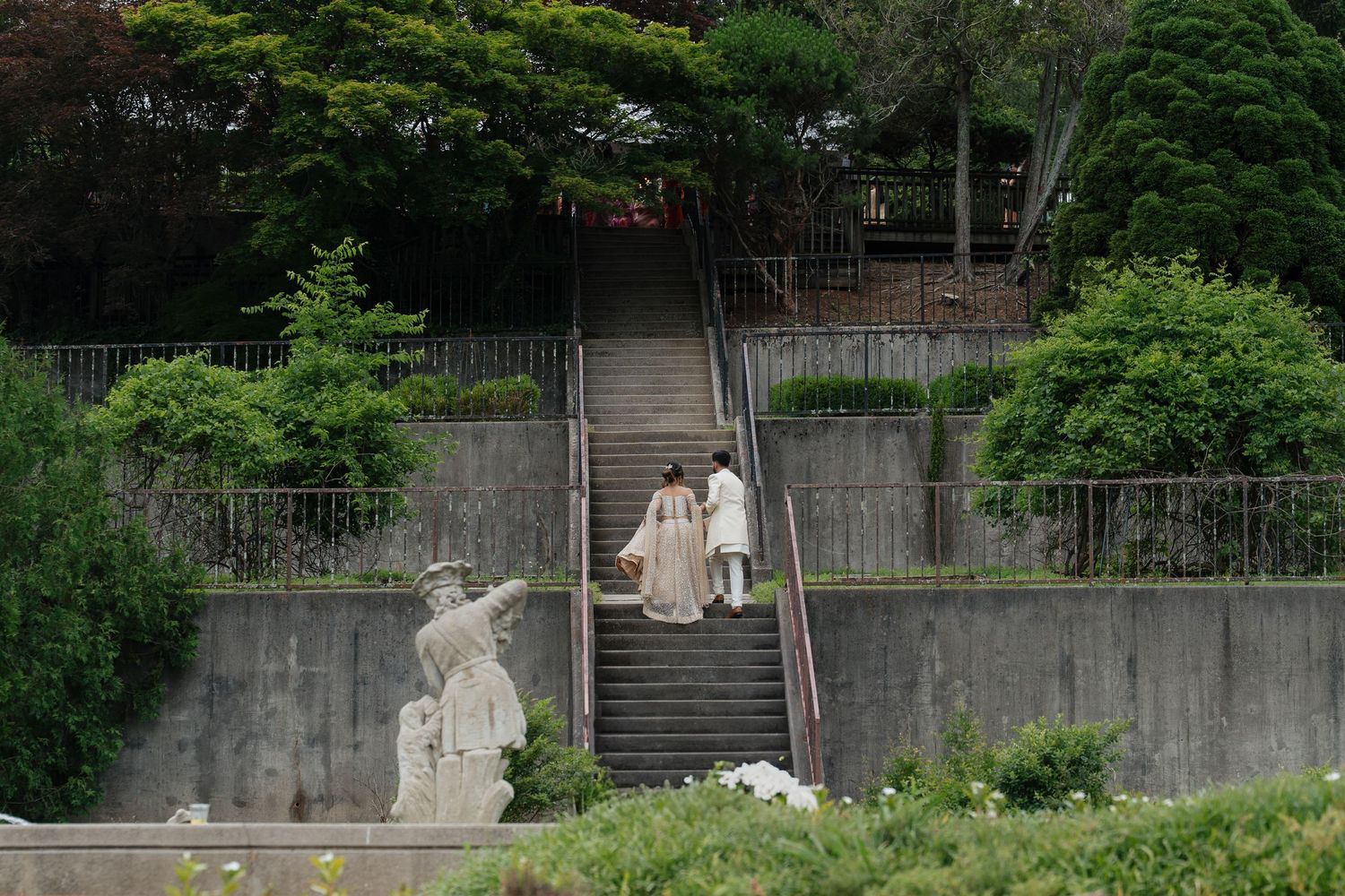 A series of seven connected security camera images showing green foliage and concrete walls in an outdoor setting.