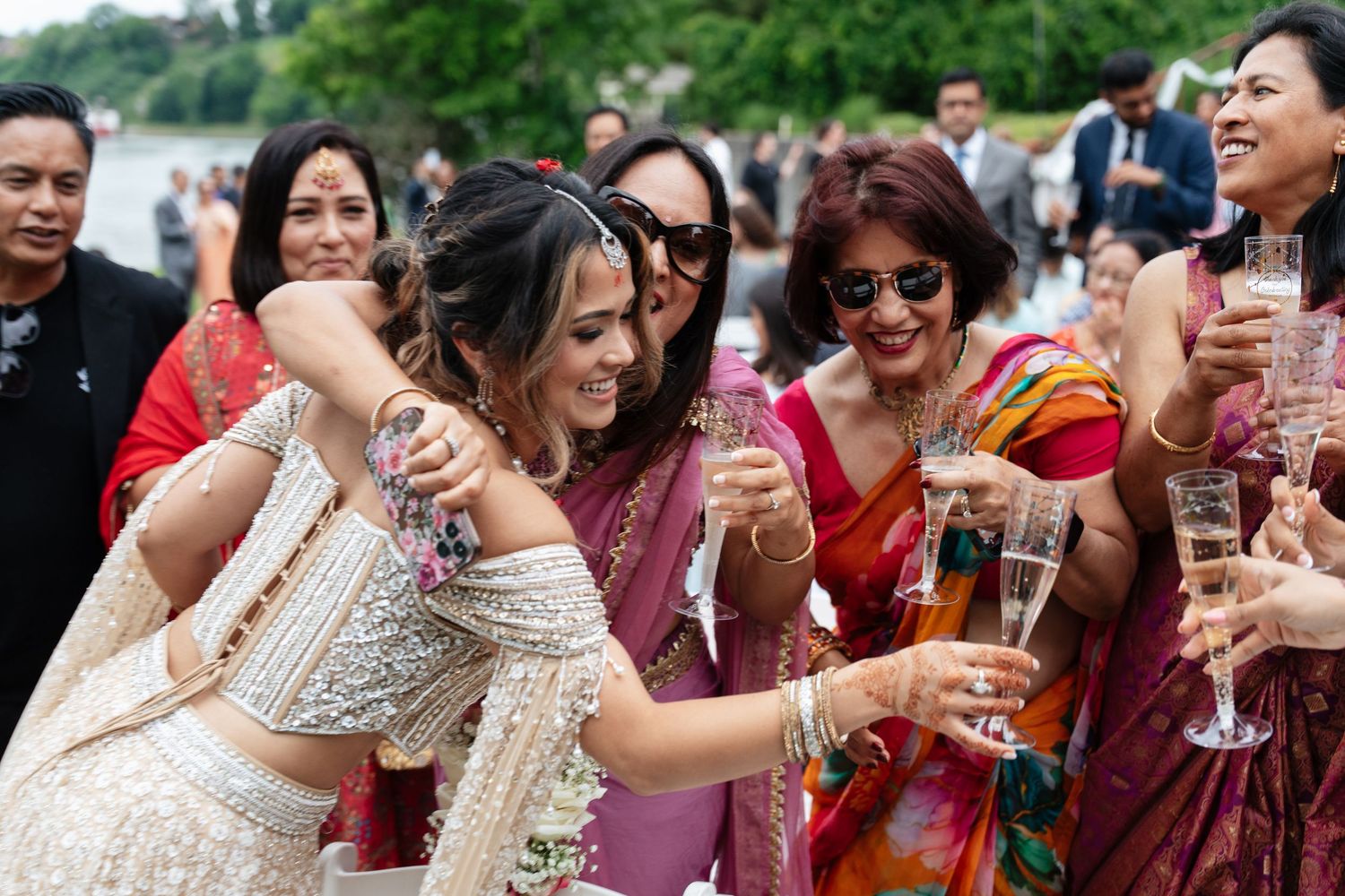 Group of people enjoying drinks and celebrating at an outdoor gathering with laughter and smiles.