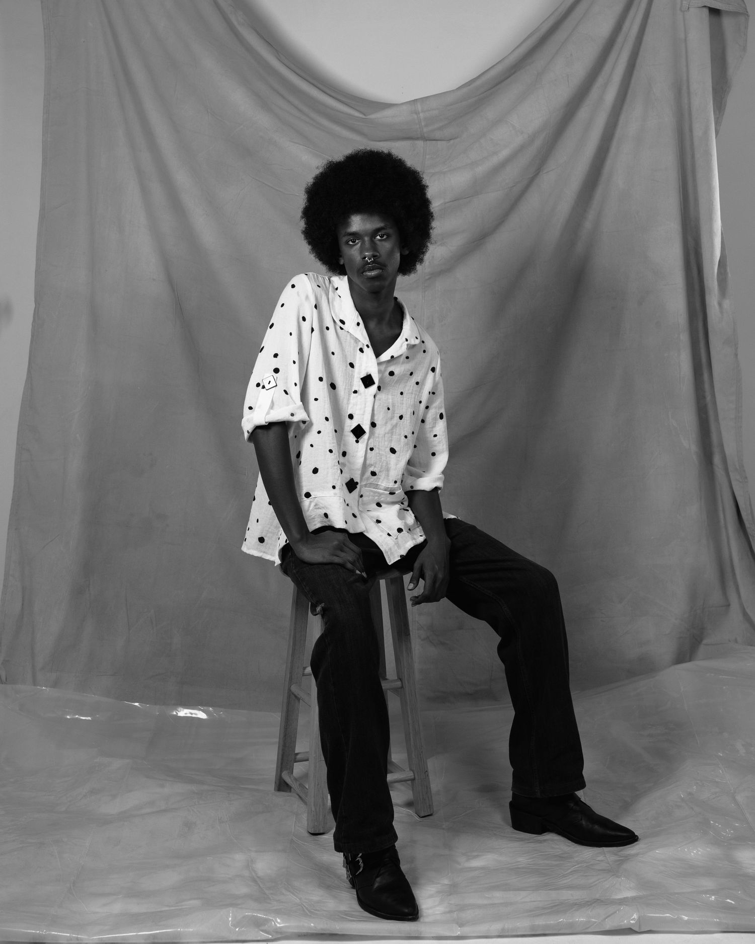 A sequence of black and white photos showing someone in a white polka dot shirt and dark pants posing against a light backdrop.