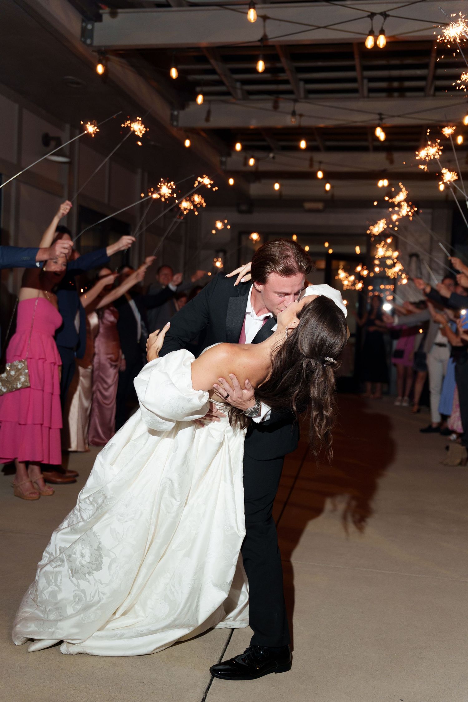 Romantic dance sequence showing a ballroom dip under twinkling string lights during a wedding reception.