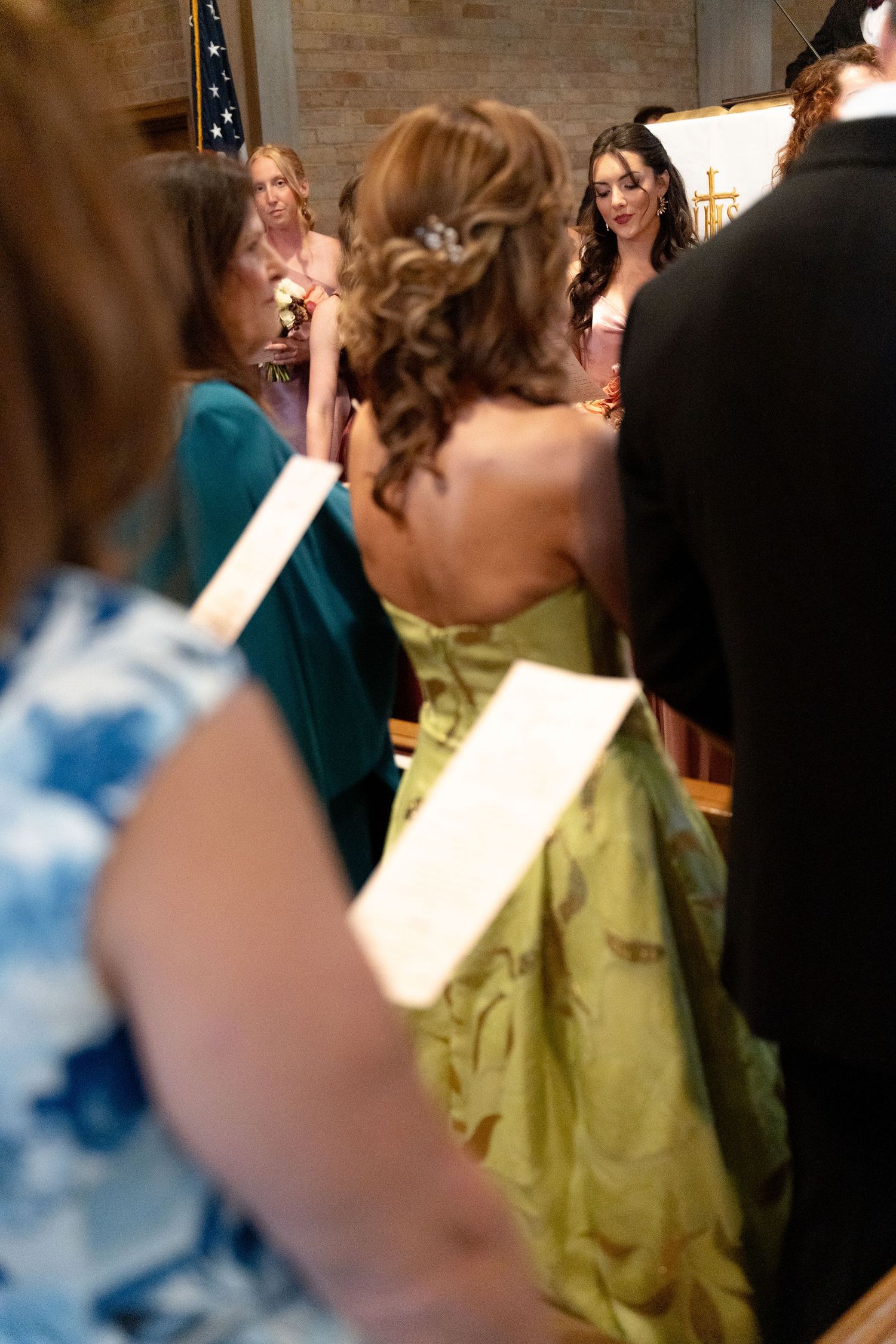 A wedding party mingles at an indoor reception with people wearing teal and lime green formal attire.