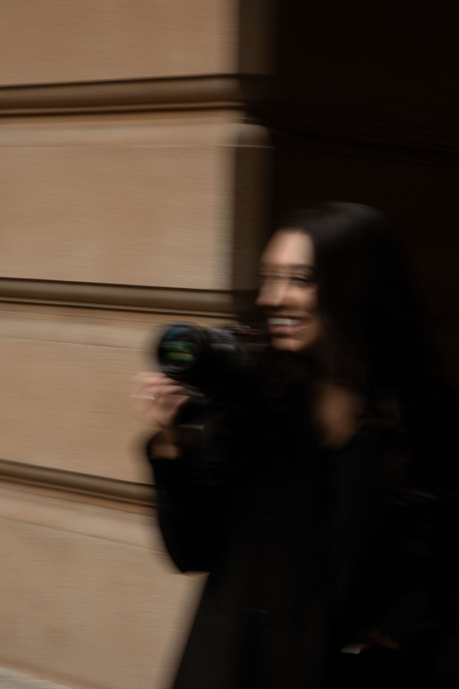 Motion blur captures dark figure moving rapidly across six sequential frames against a beige wall background.