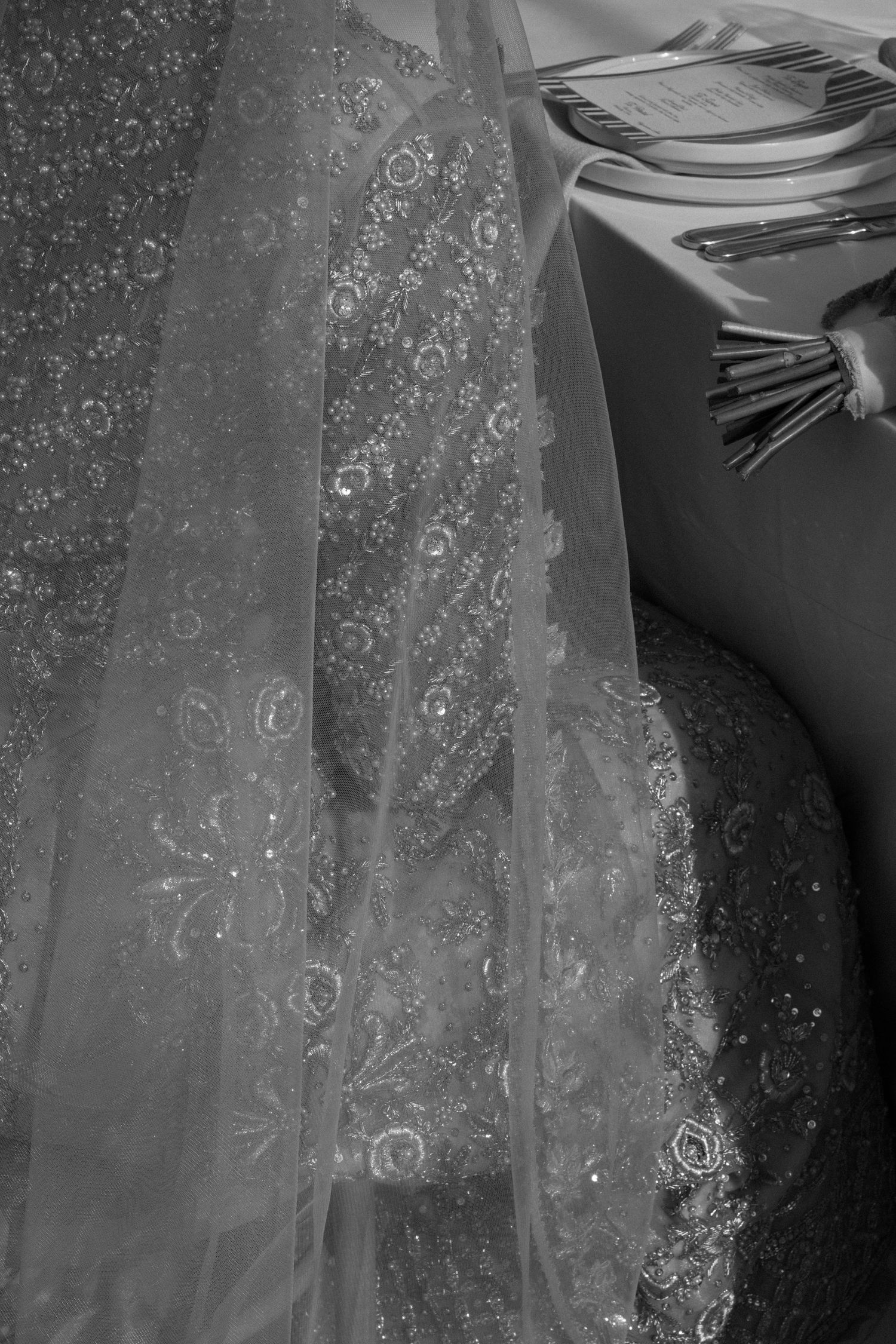 Close-up black and white photo of intricate embroidered lace wedding veil with floral details.
