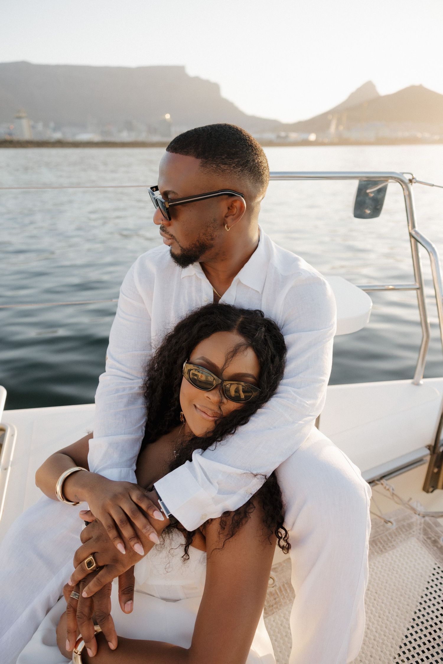 A romantic moment captured on a boat with the ocean and mountains in the background.