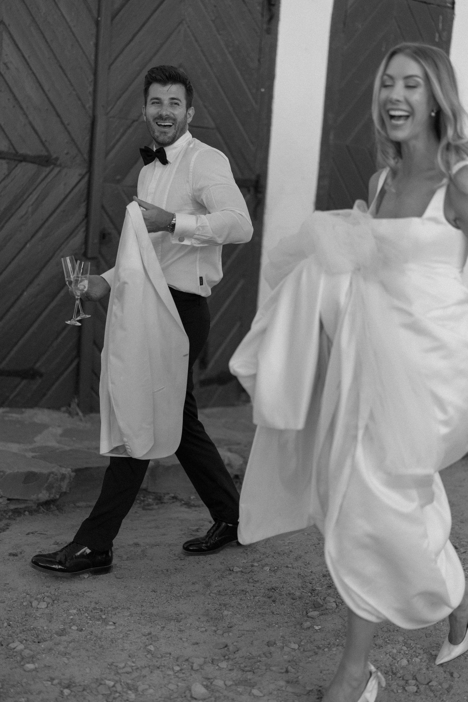 A black and white photo sequence shows a couple dancing playfully in wedding attire outside a rustic barn.