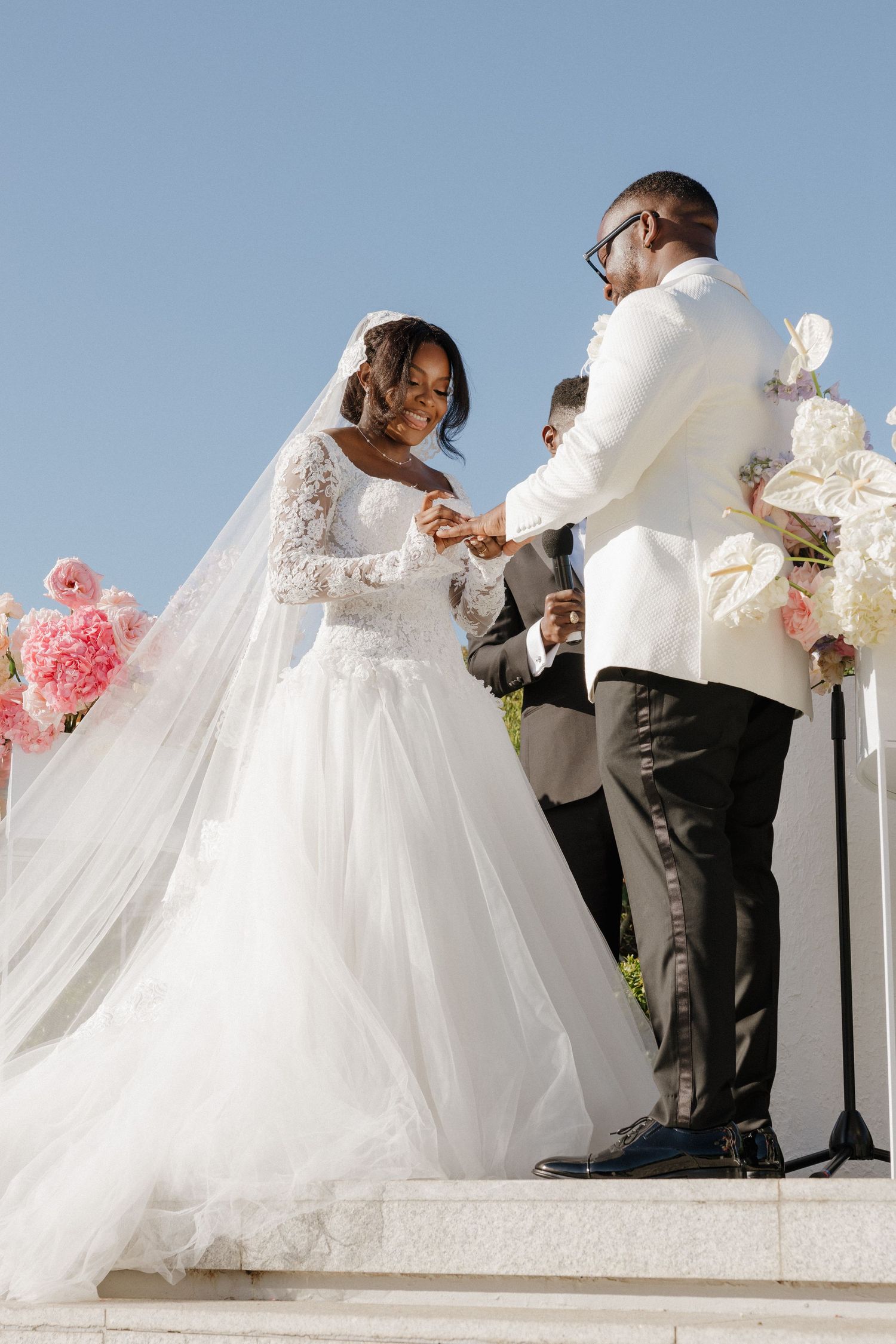 A bride and groom are standing on a platform, surrounded by their wedding party.