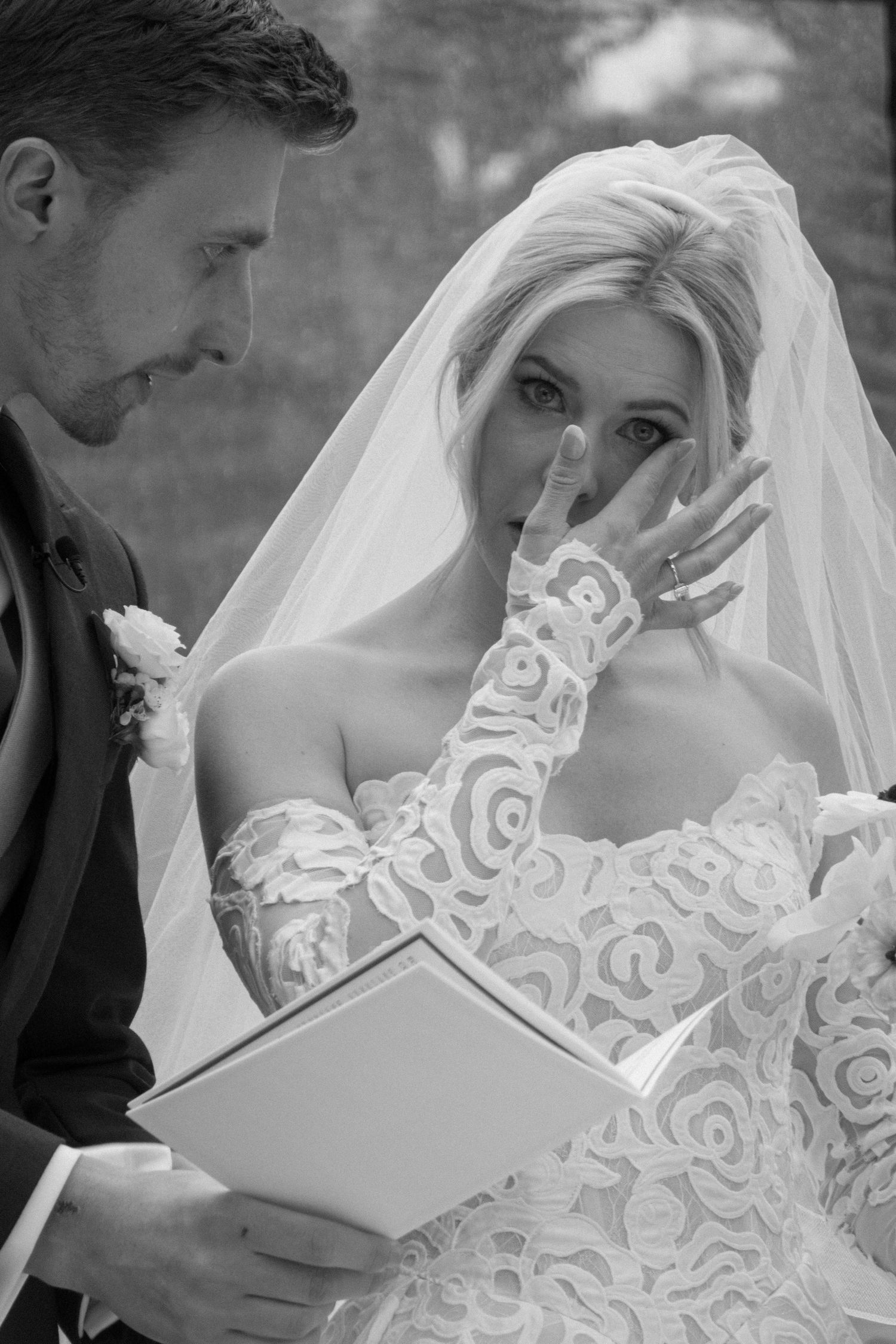 Black and white wedding photos showing tender moments between a bride in lace dress and groom during their ceremony.