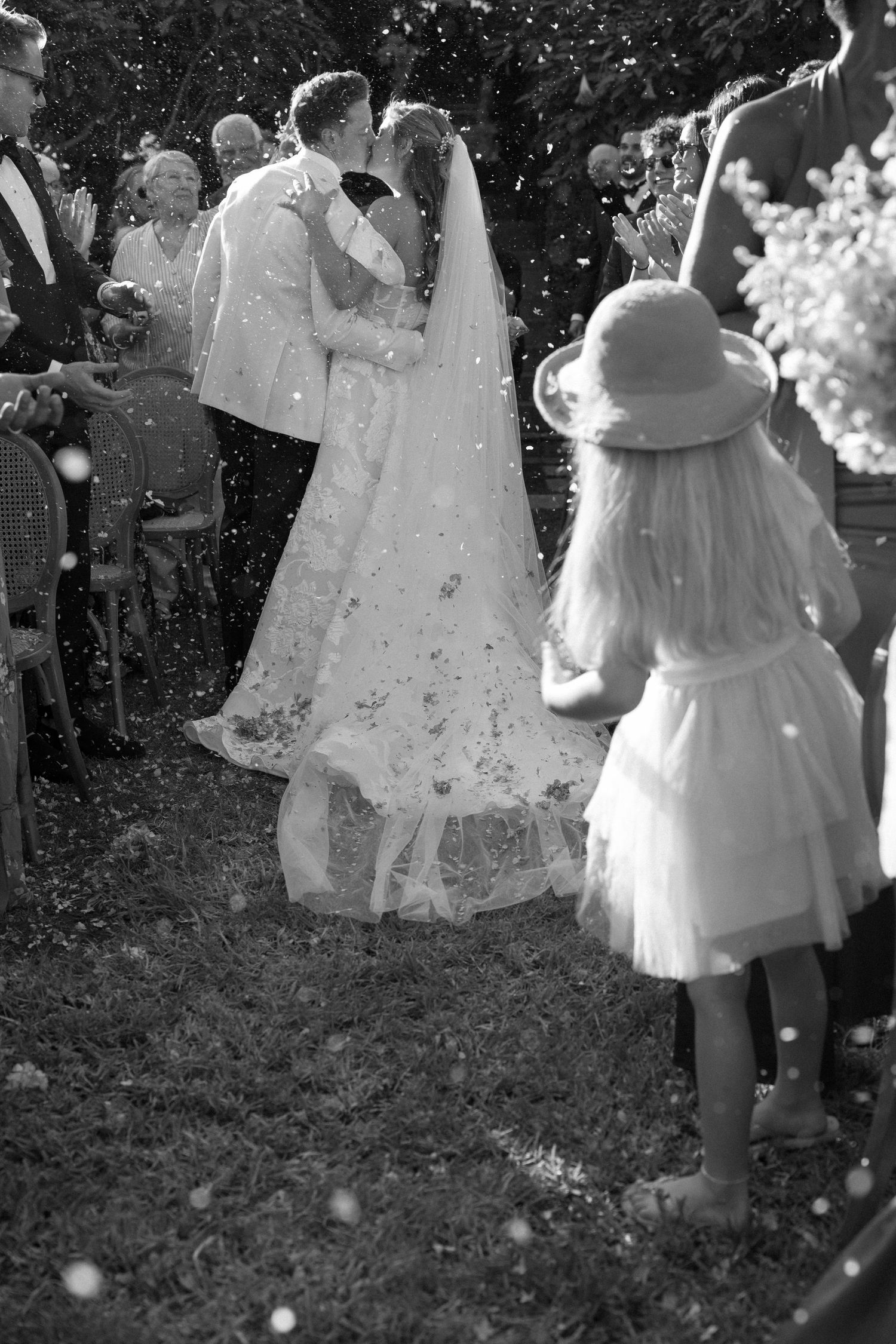 A series of black and white photographs showing people in white dresses walking through a garden setting.