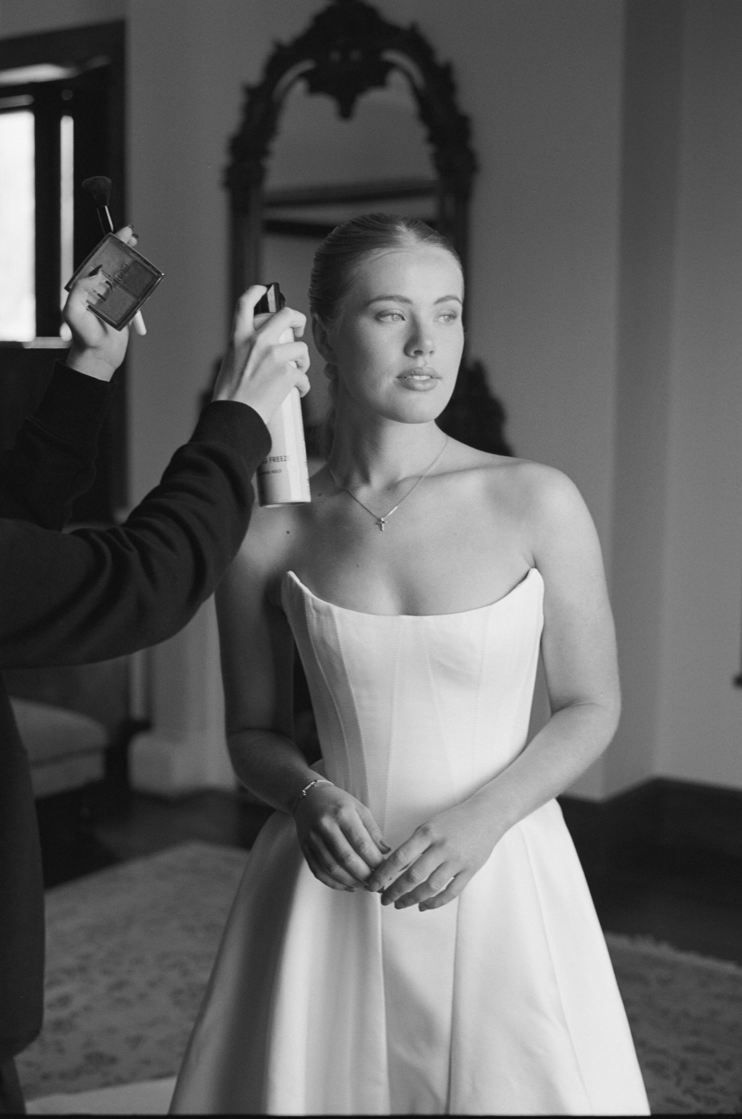 A series of black and white photos showing someone getting dressed in a white wedding gown.