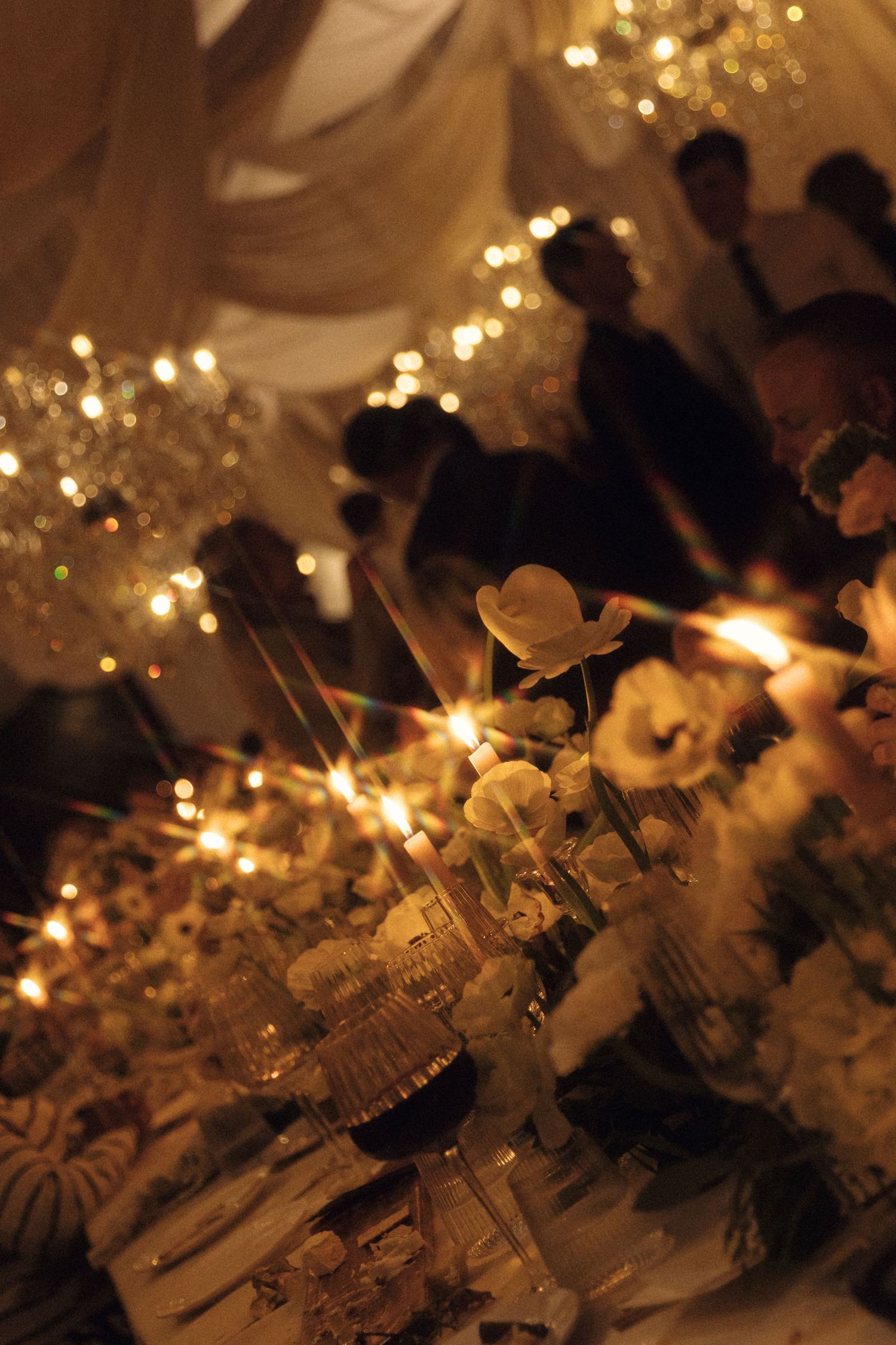 Sparklers create a magical glow against a dark background with bokeh lights twinkling in the distance.